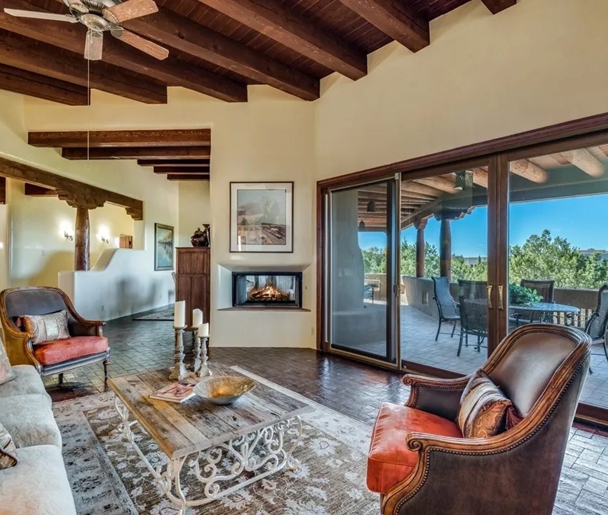 Spacious living room with rustic ceiling and large glass doors opening to a scenic outdoor view.