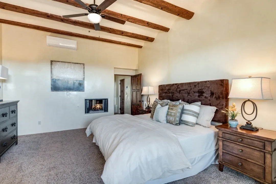 Cozy bedroom with exposed wooden beams and a fireplace.