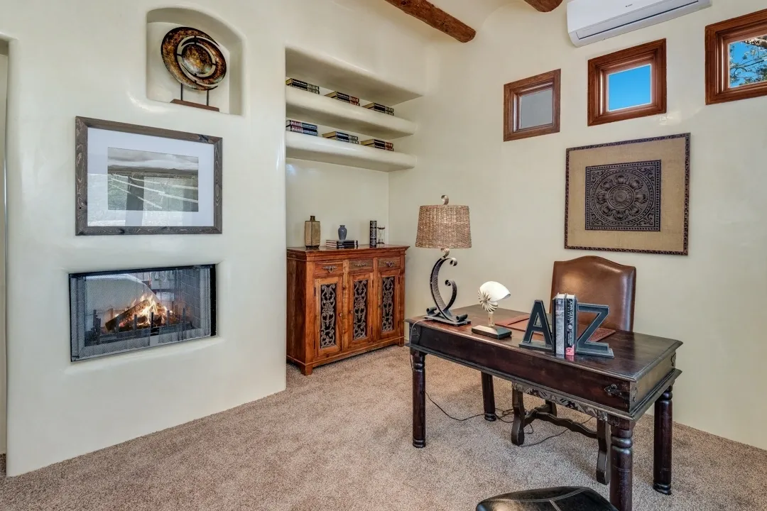 Cozy home office with wooden beams and a fireplace.