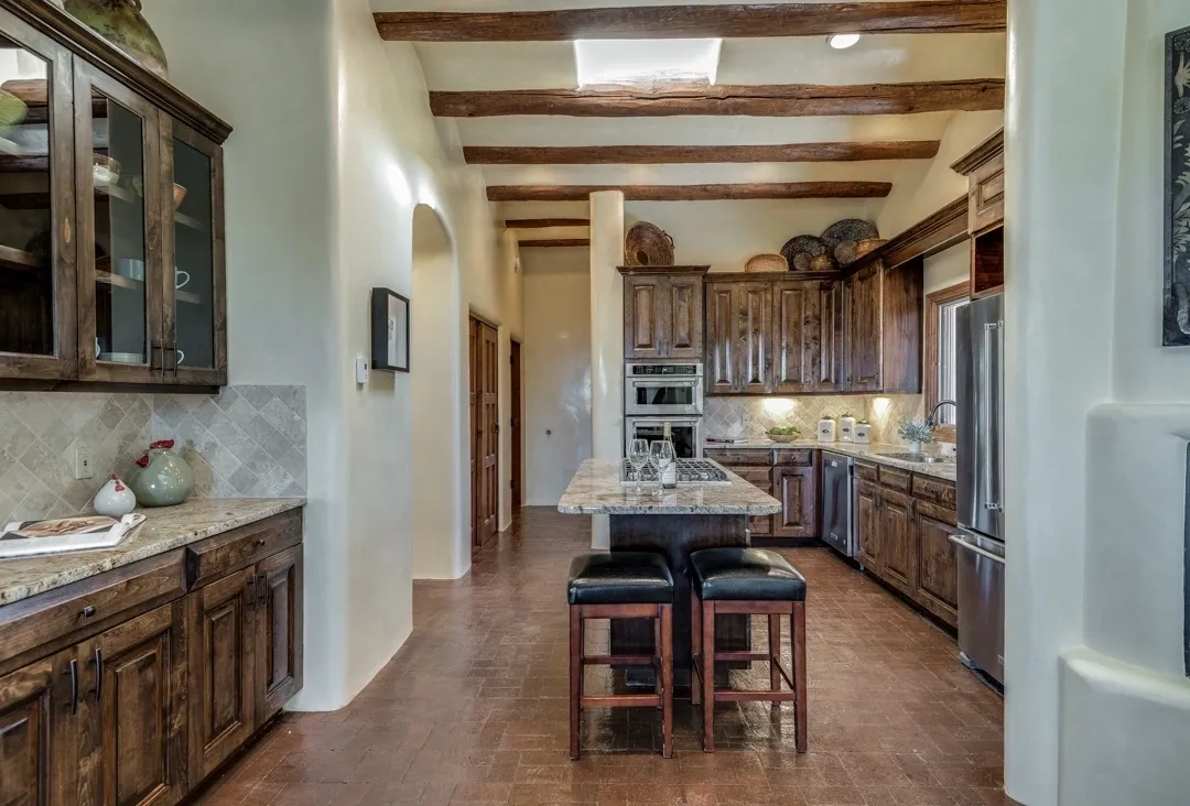 Rustic kitchen with wooden beams and central island seating.