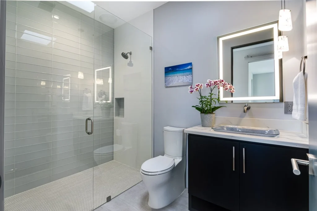 Modern bathroom with glass shower and dark vanity.