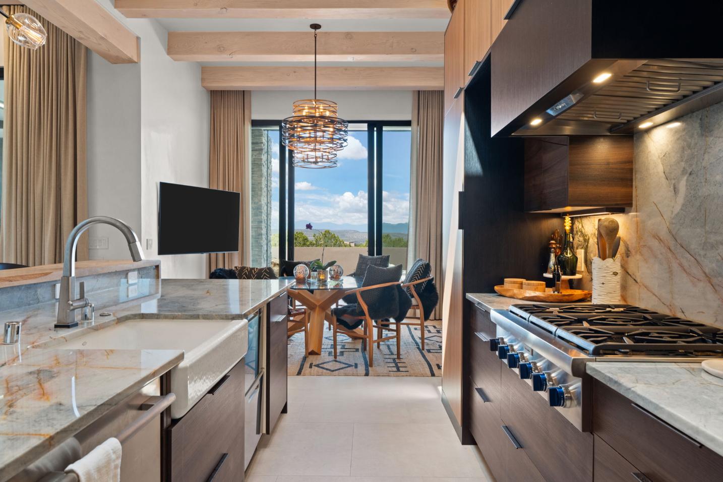 Modern kitchen with sleek appliances and a dining area overlooking a scenic view.