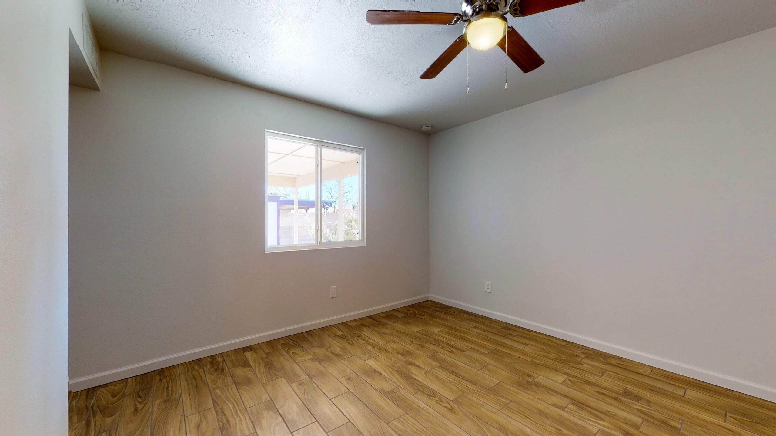 Empty room with wooden floor and ceiling fan.