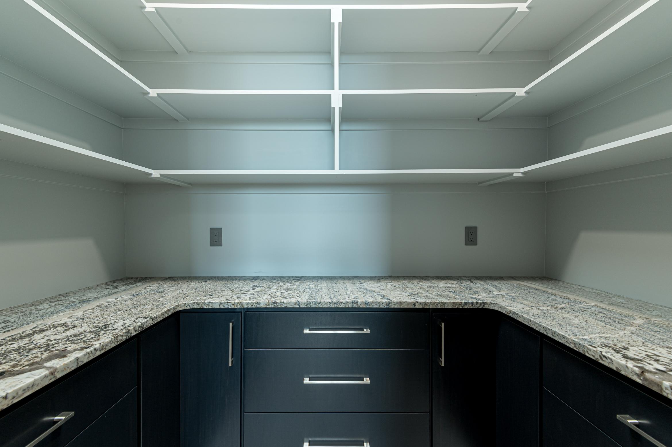 Empty kitchen corner with granite countertop and black cabinets.