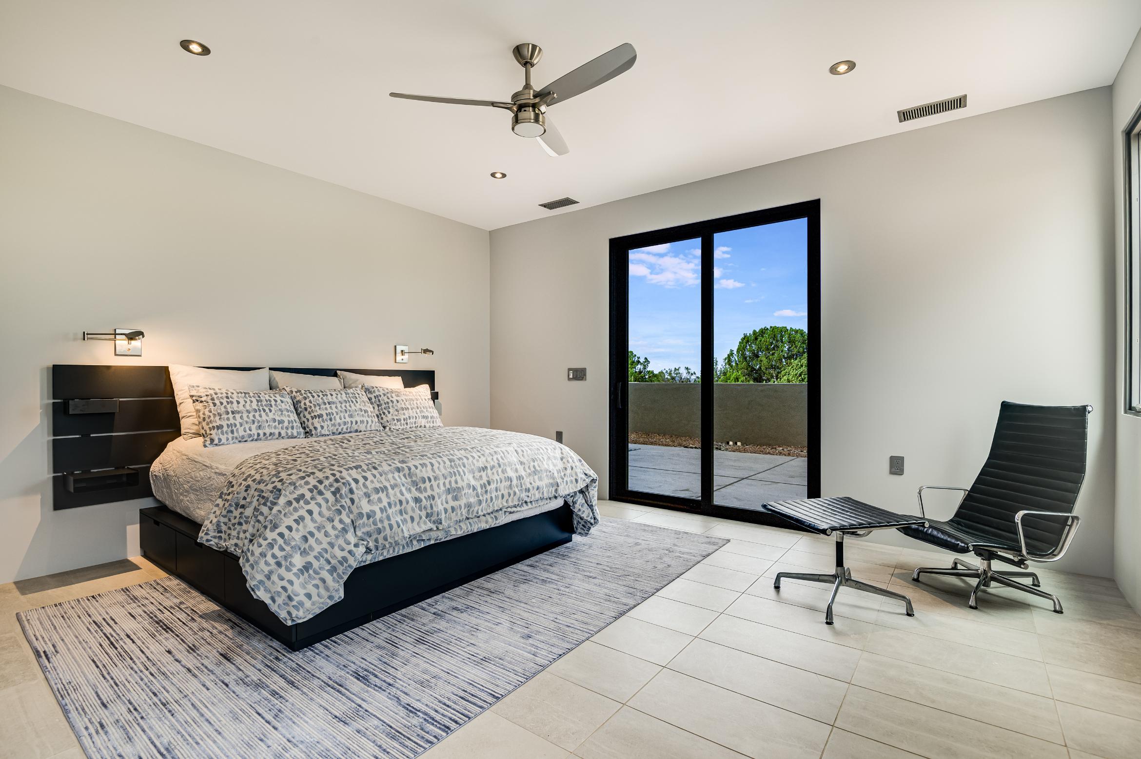Modern bedroom with a large bed and glass doors opening to a balcony.