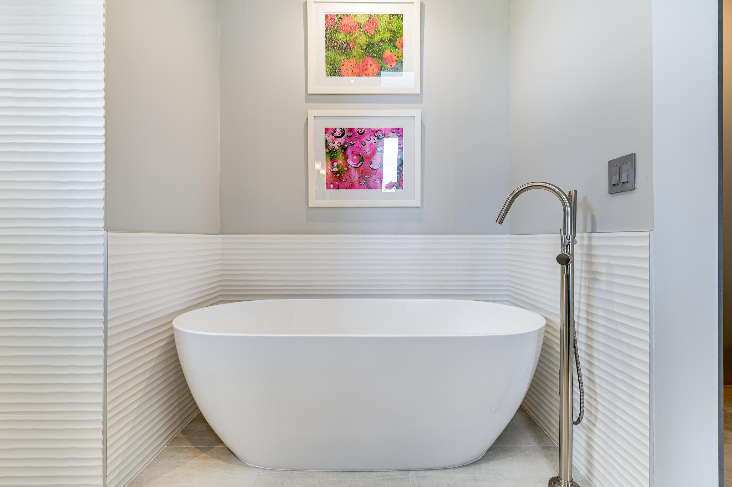 Modern white freestanding bathtub in a minimalist bathroom.