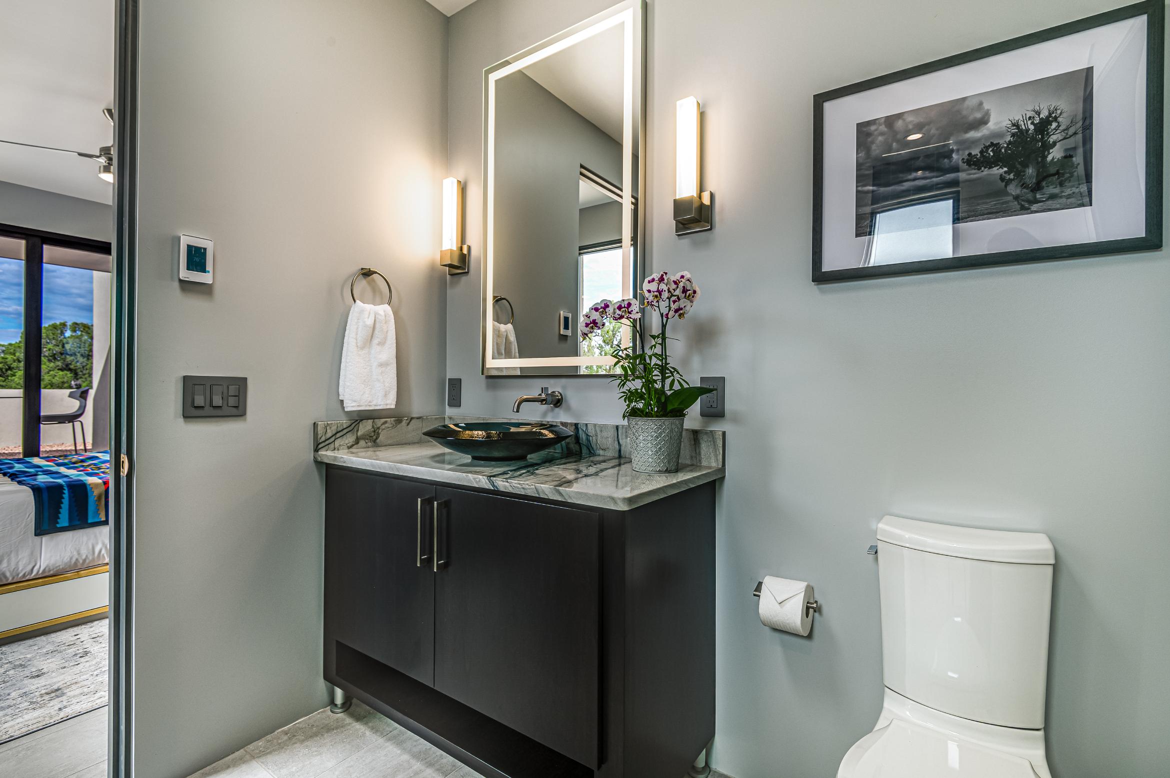 Modern bathroom with dark vanity and illuminated mirror.