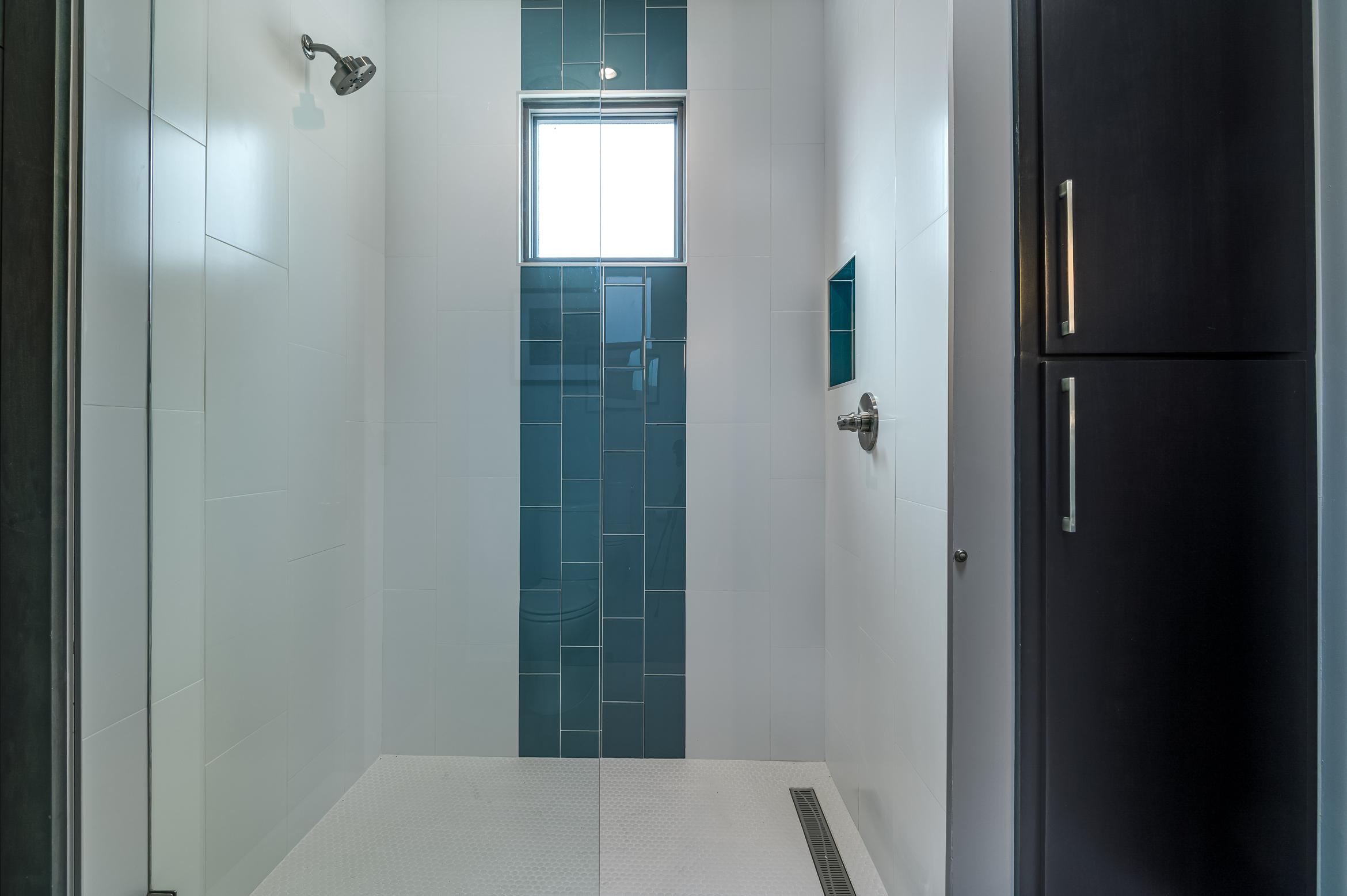 Minimalist bathroom with a walk-in shower and dark blue tile accent wall.
