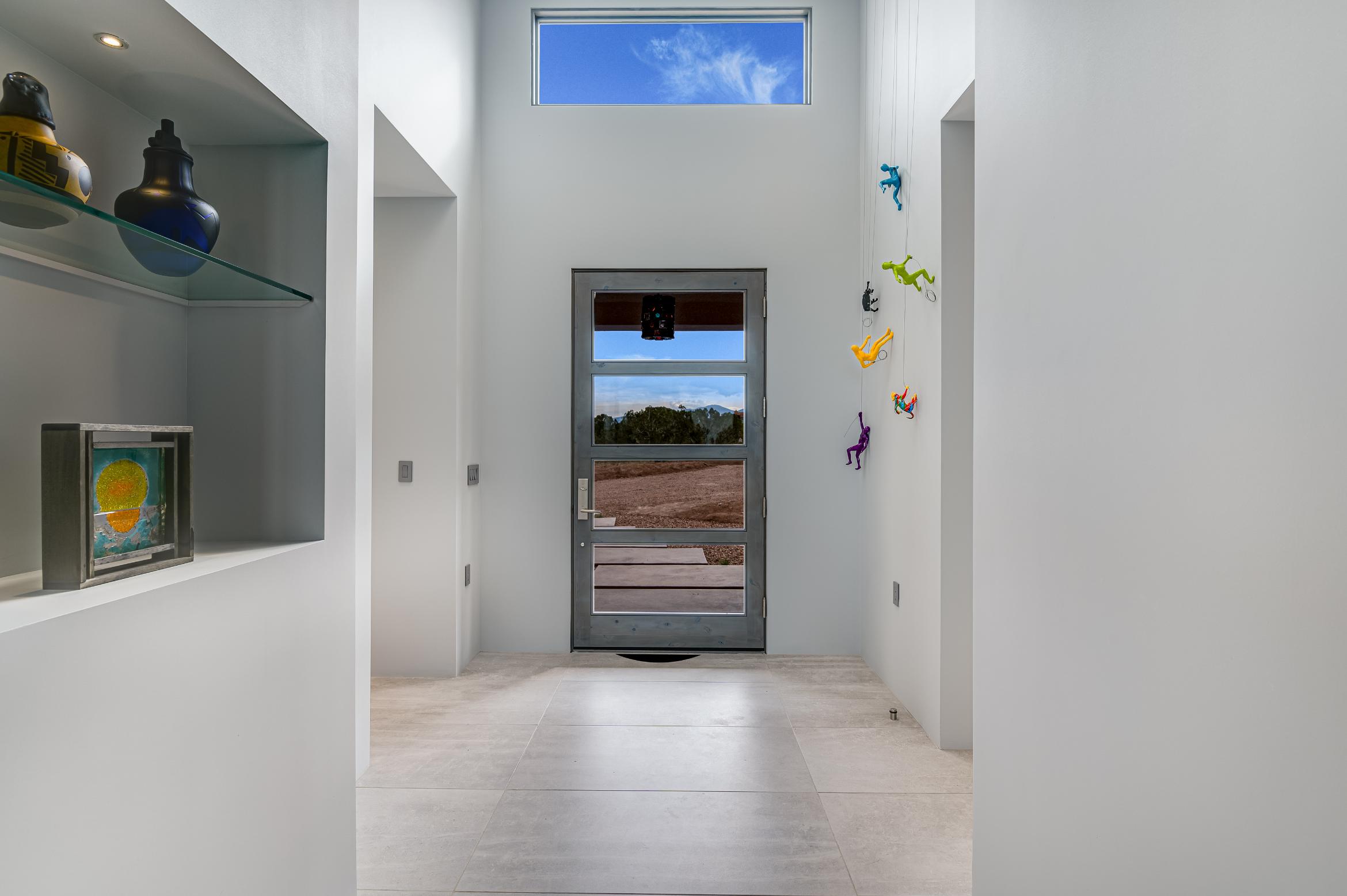 Minimalist hallway with glass door and colorful wall decorations.