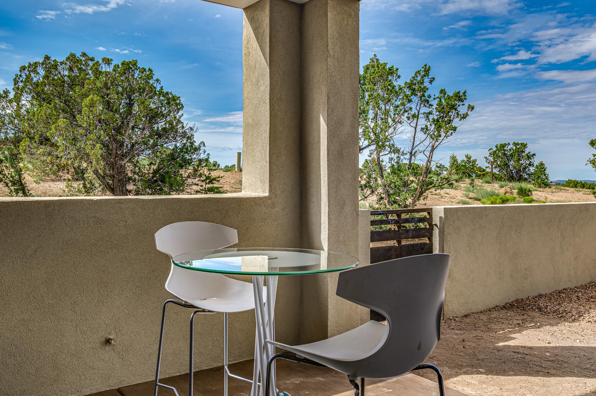 Modern outdoor seating with two chairs and a glass table on a balcony.