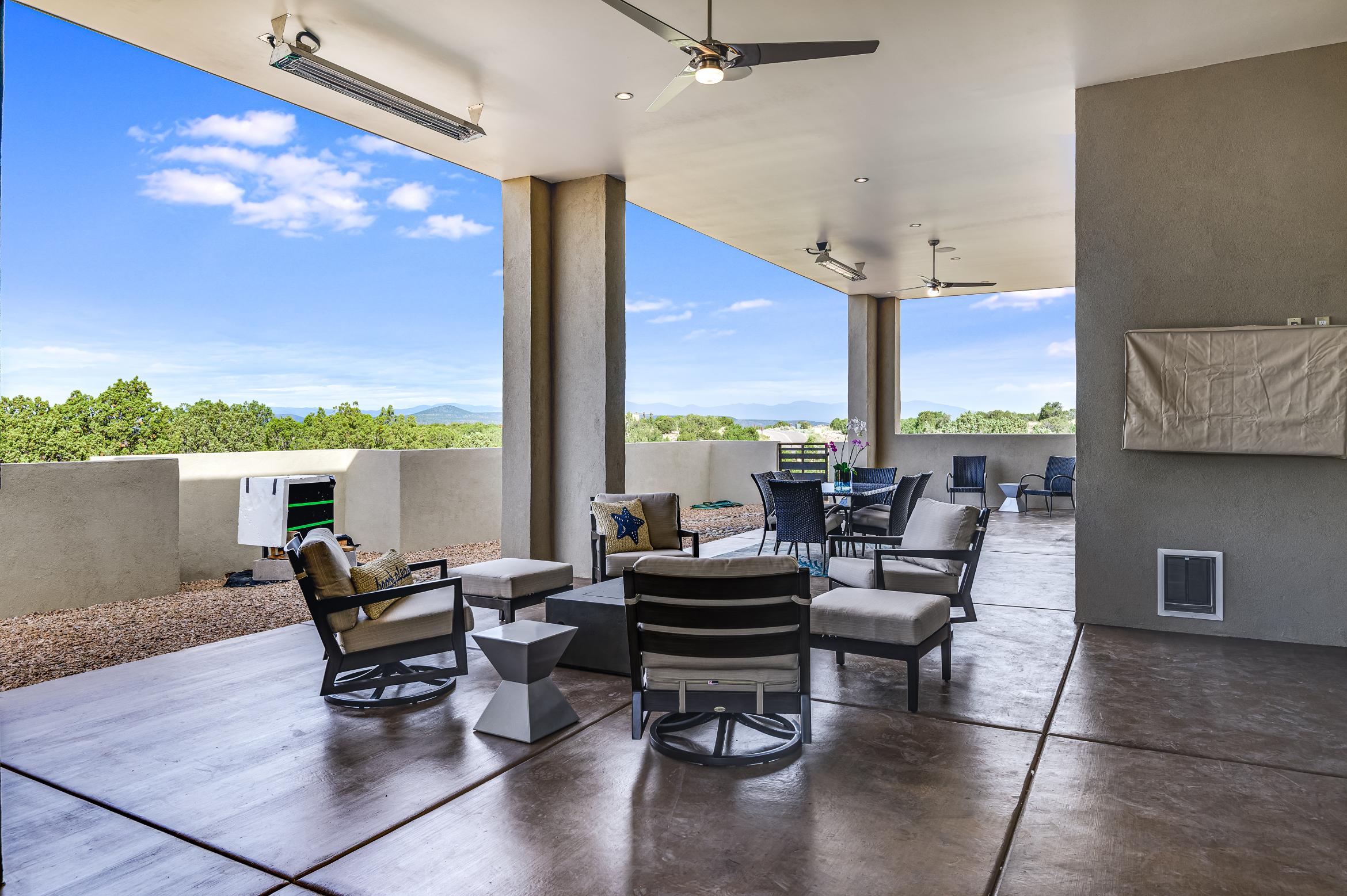 Spacious outdoor patio with modern seating and ceiling fans under a clear blue sky.