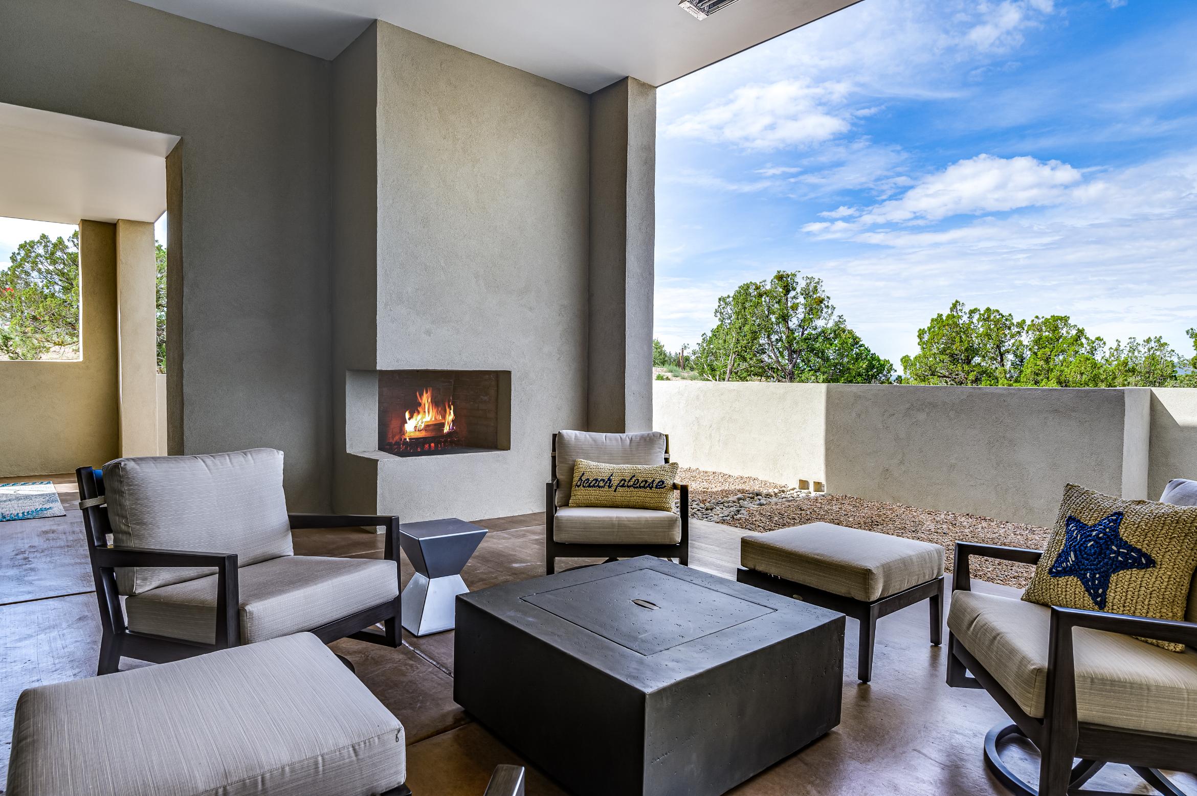 Modern patio with cozy seating and a fireplace under a bright sky.