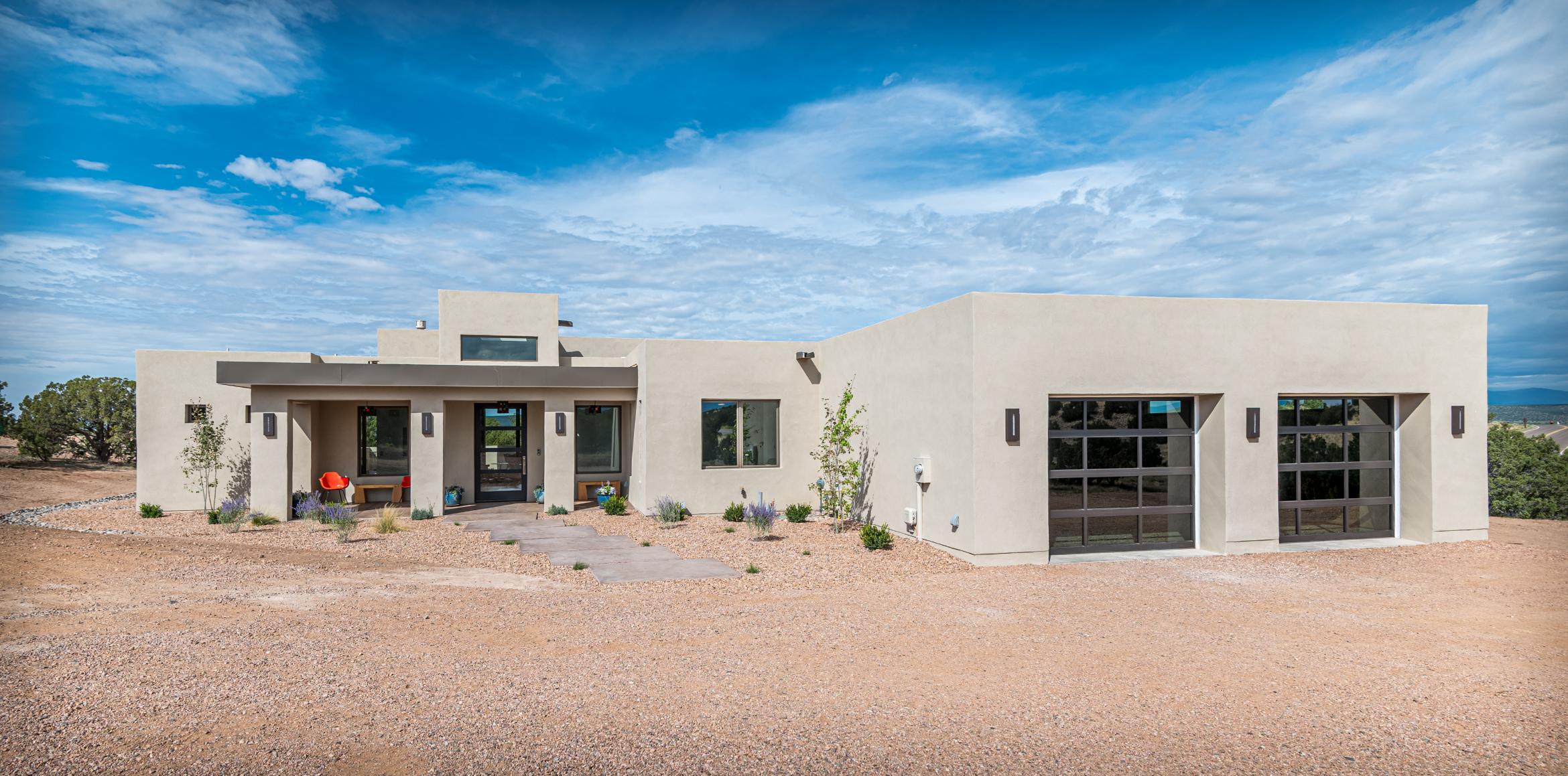 Modern single-story house with a desert landscape and blue sky.