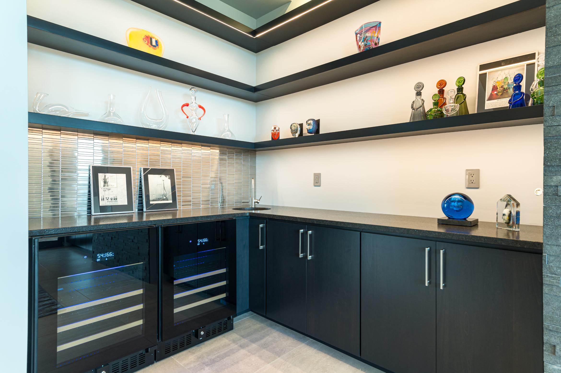 Modern kitchen corner with black cabinets and built-in wine cooler.