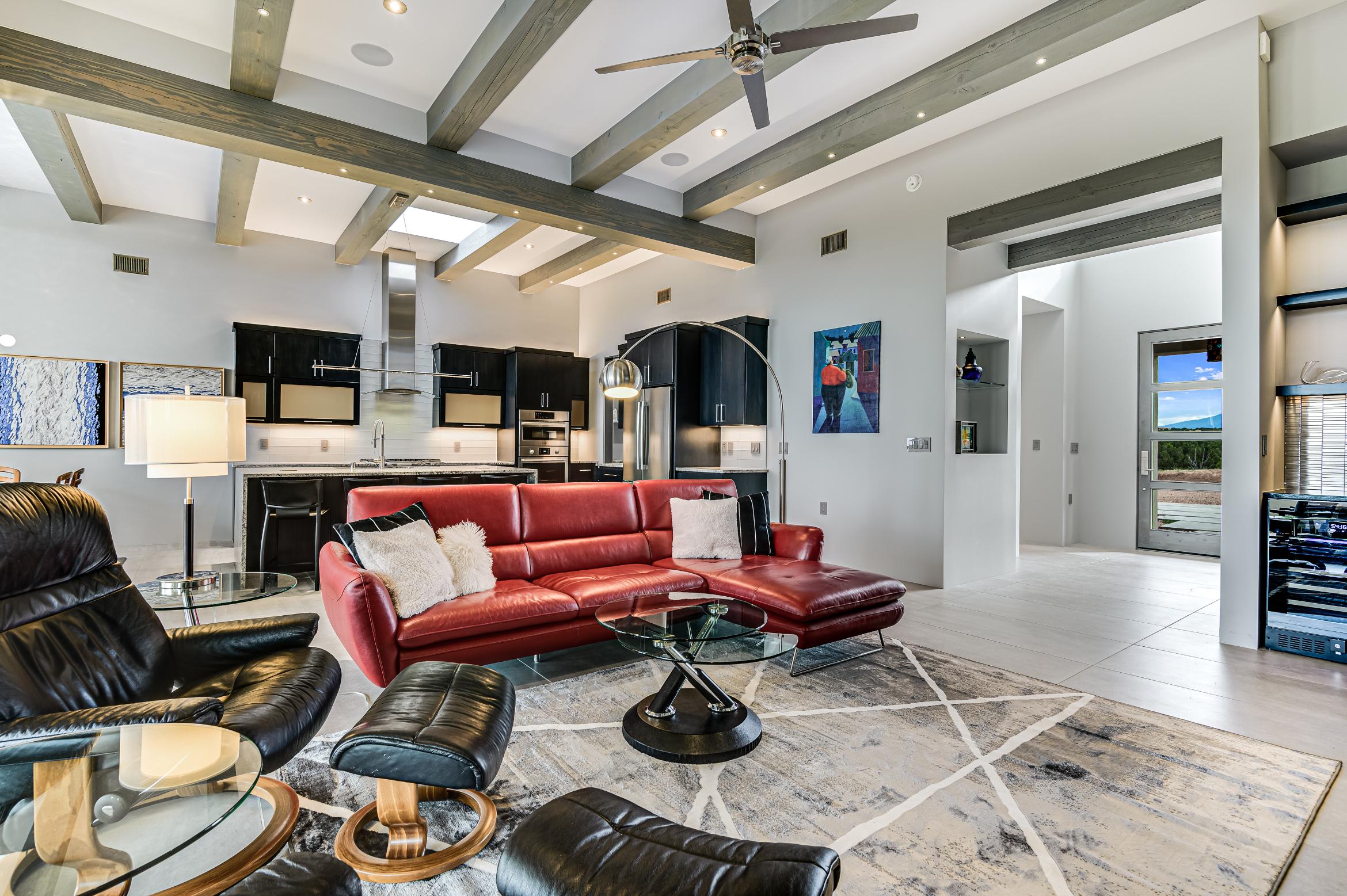 Modern living room with red leather sectional and exposed beams.