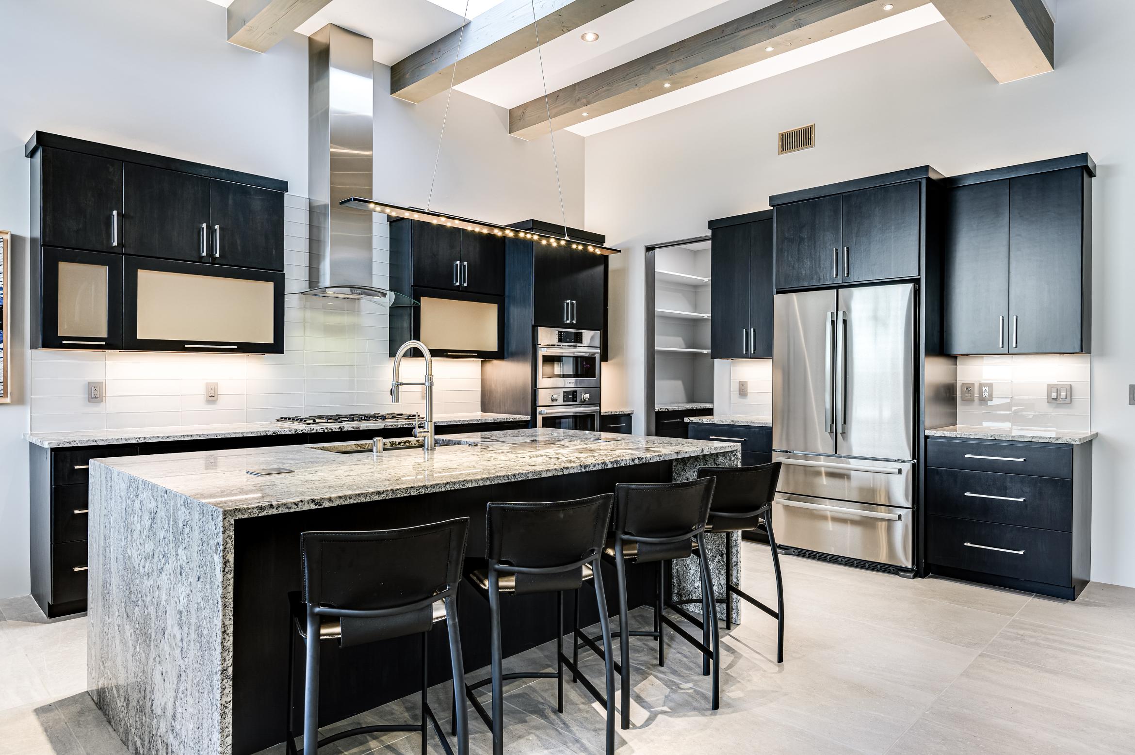 Modern kitchen with black cabinetry and a large island with bar stools.