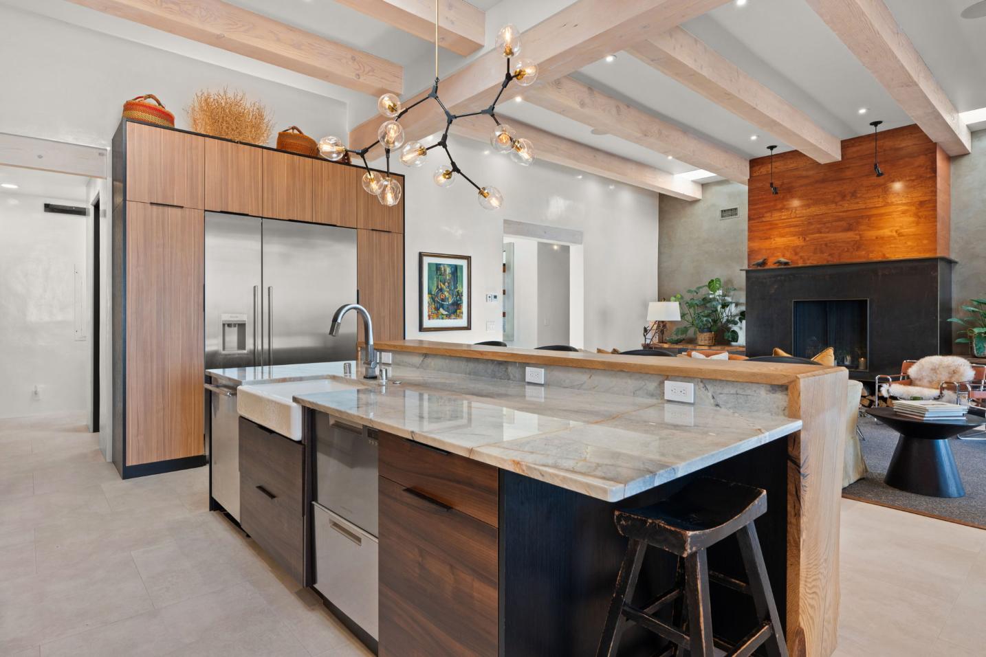 Modern kitchen with large marble island and contemporary lighting.
