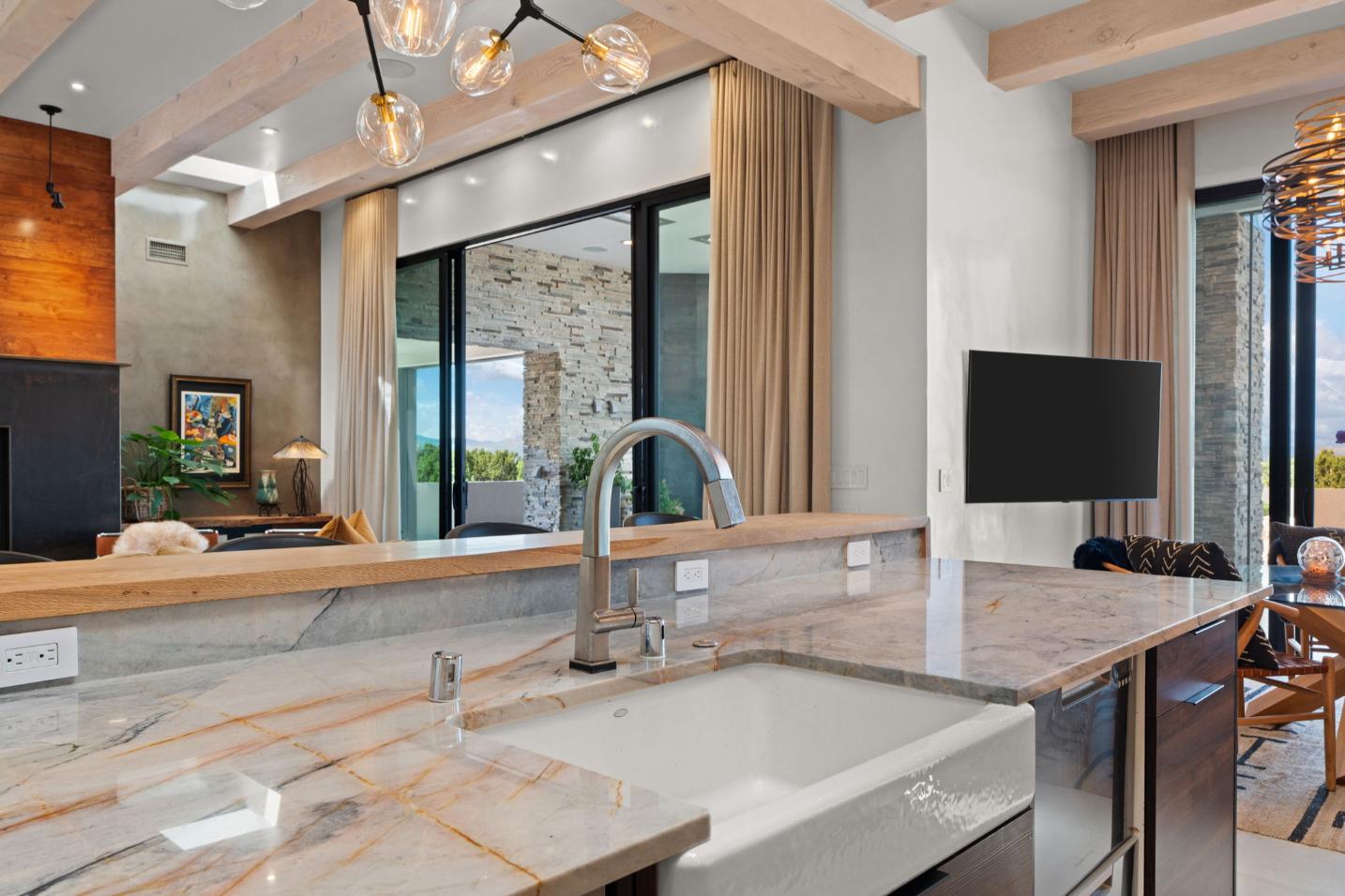 Modern kitchen sink area with marble countertop and large window.
