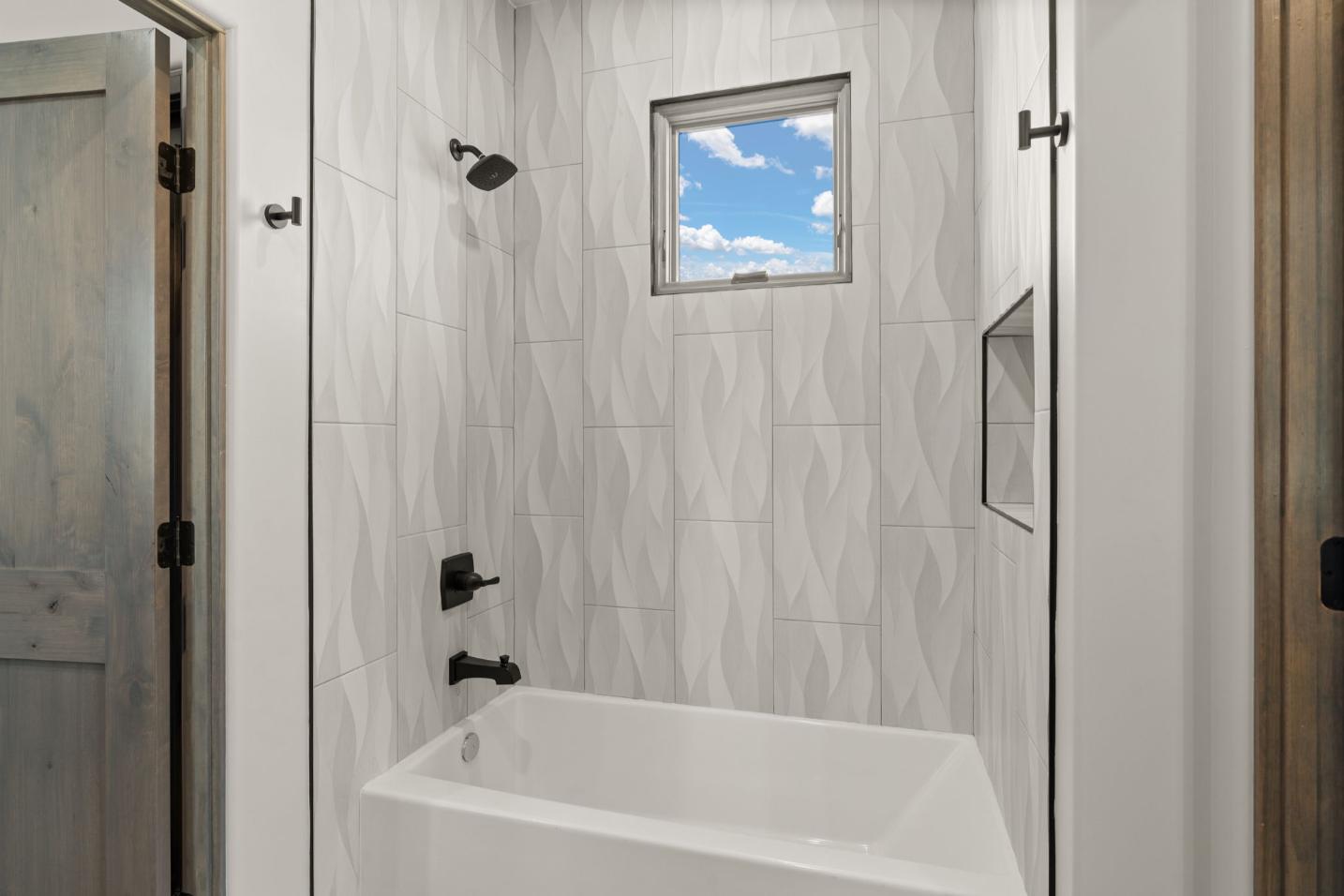 Modern white bathroom with black fixtures and a small window.