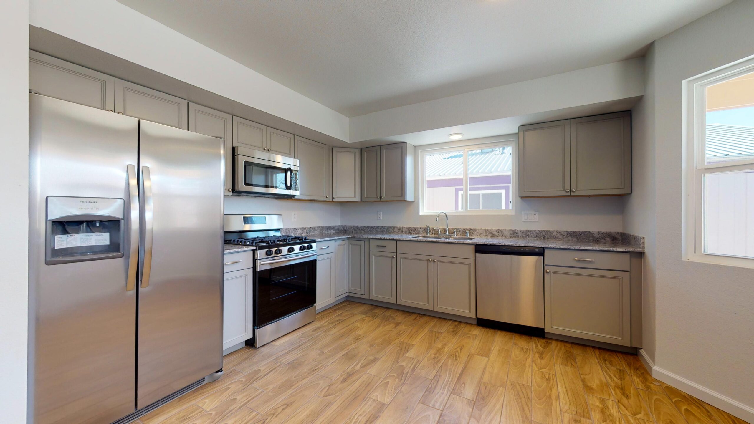 Modern kitchen with stainless steel appliances and wooden flooring.