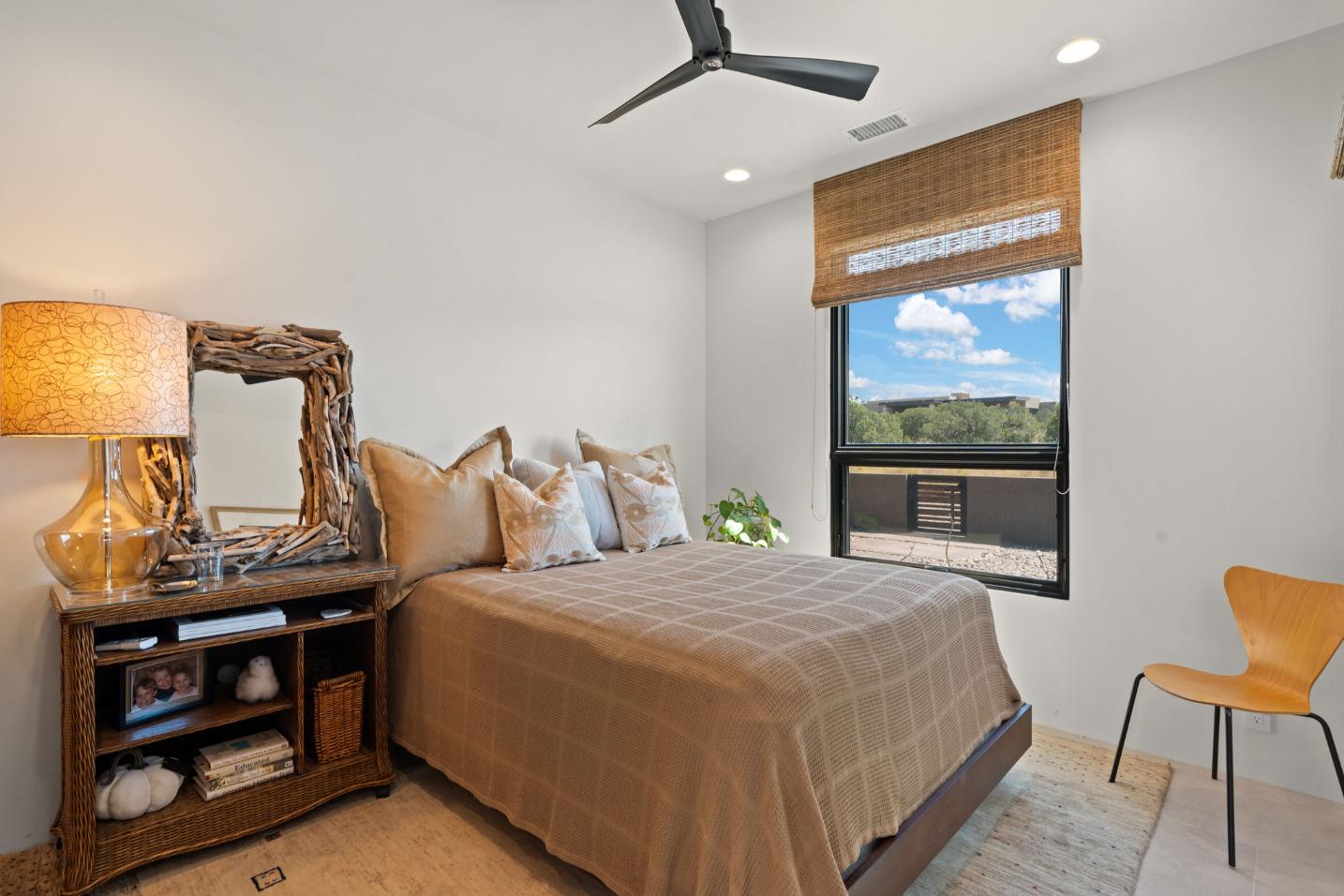Cozy bedroom with neutral tones, a large window, and a ceiling fan.