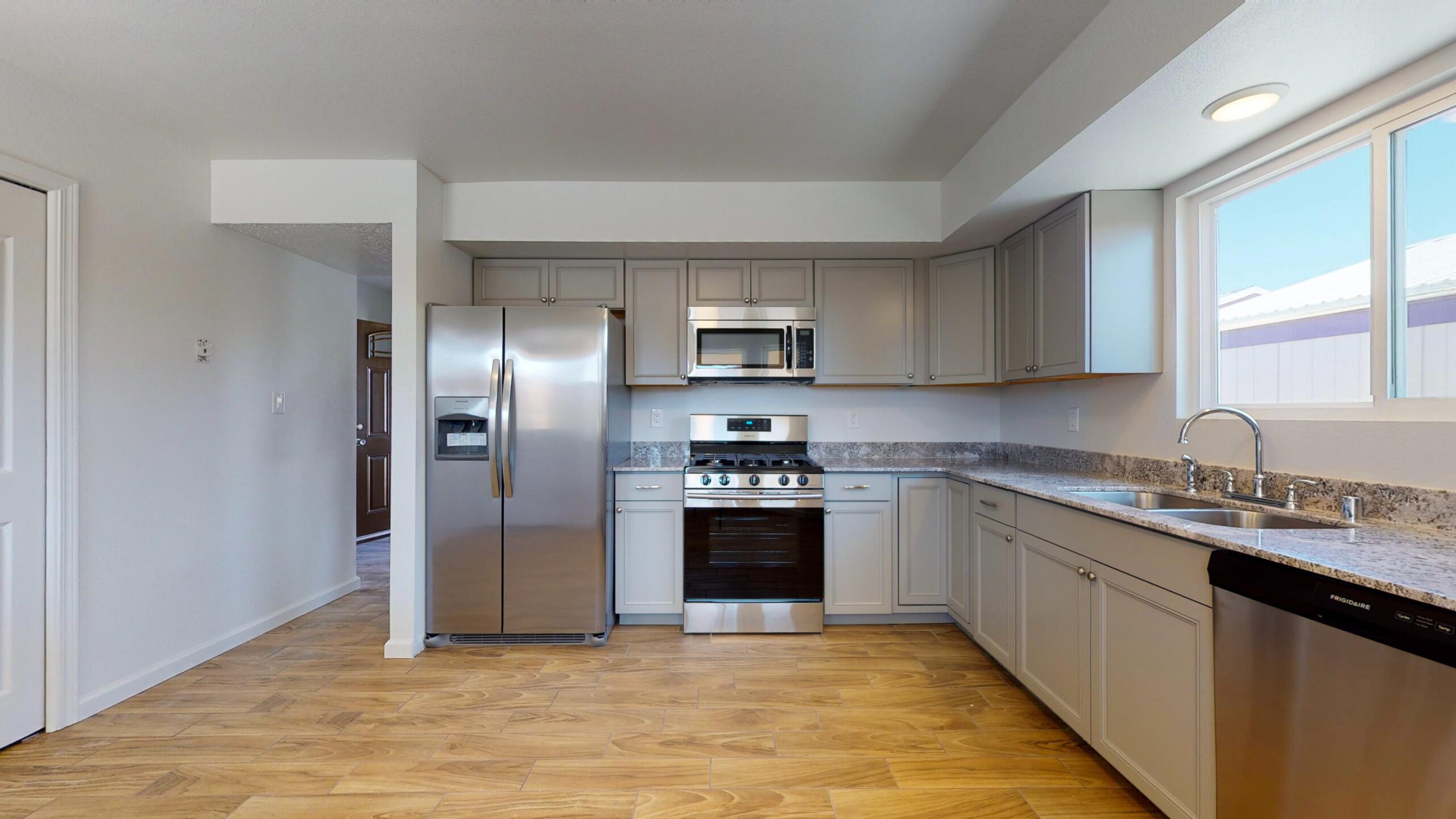 Modern kitchen with stainless steel appliances and wooden flooring.
