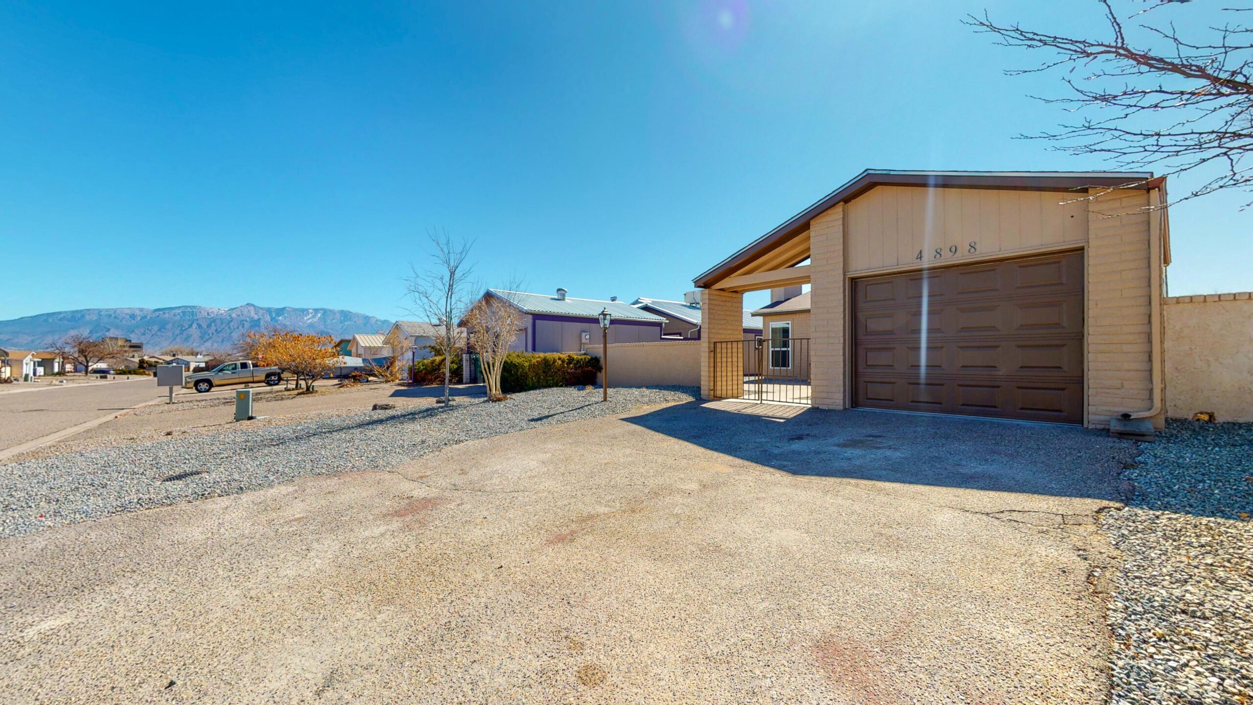 Spacious driveway and garage under a clear blue sky in a residential area.