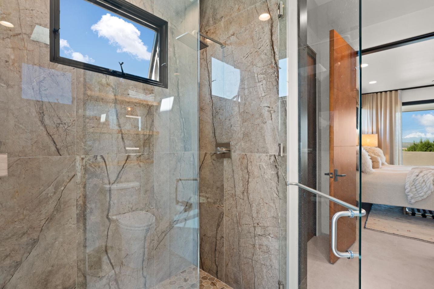 Modern bathroom with glass shower and marble walls.