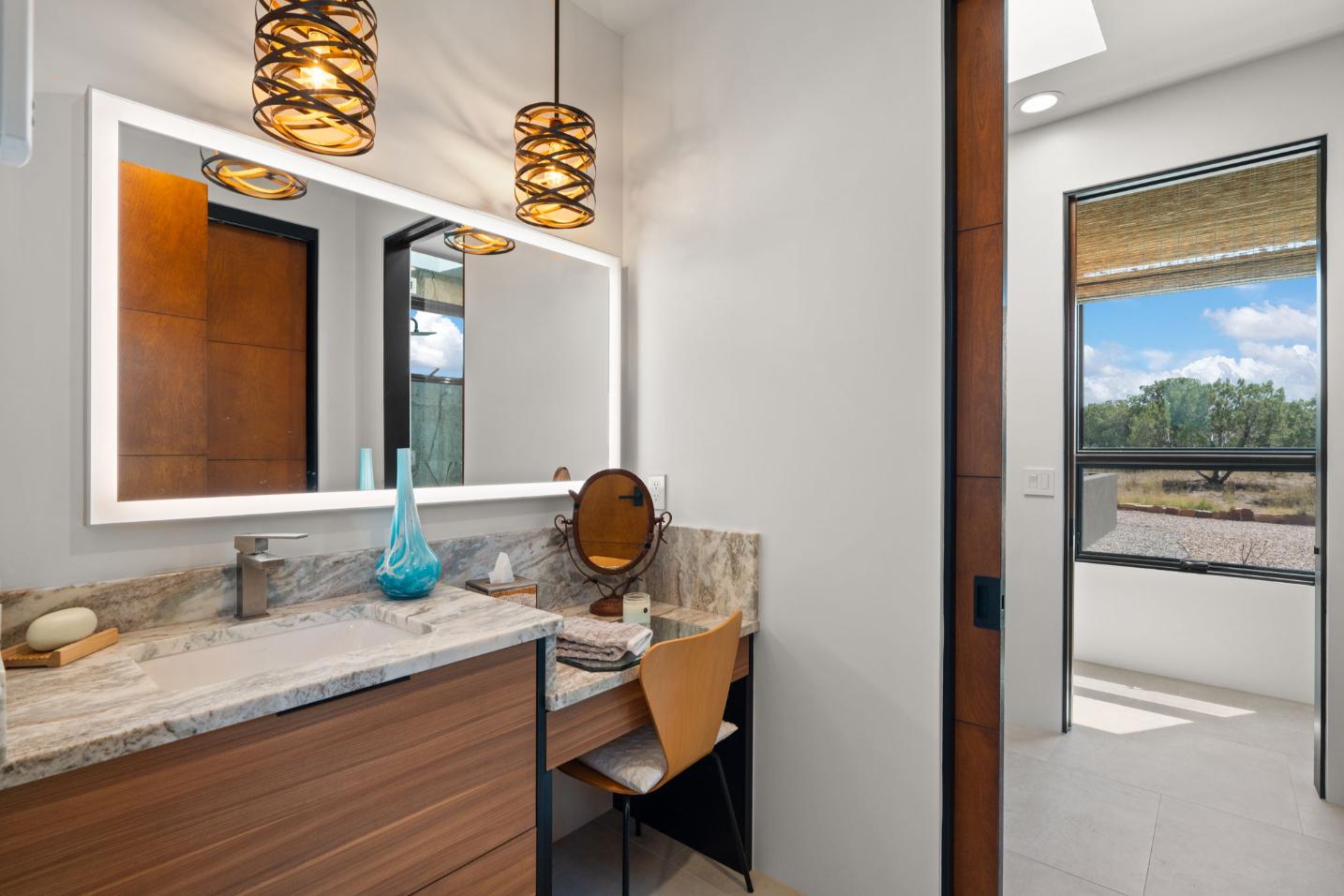Modern bathroom vanity with wooden cabinets and decorative pendant lights.