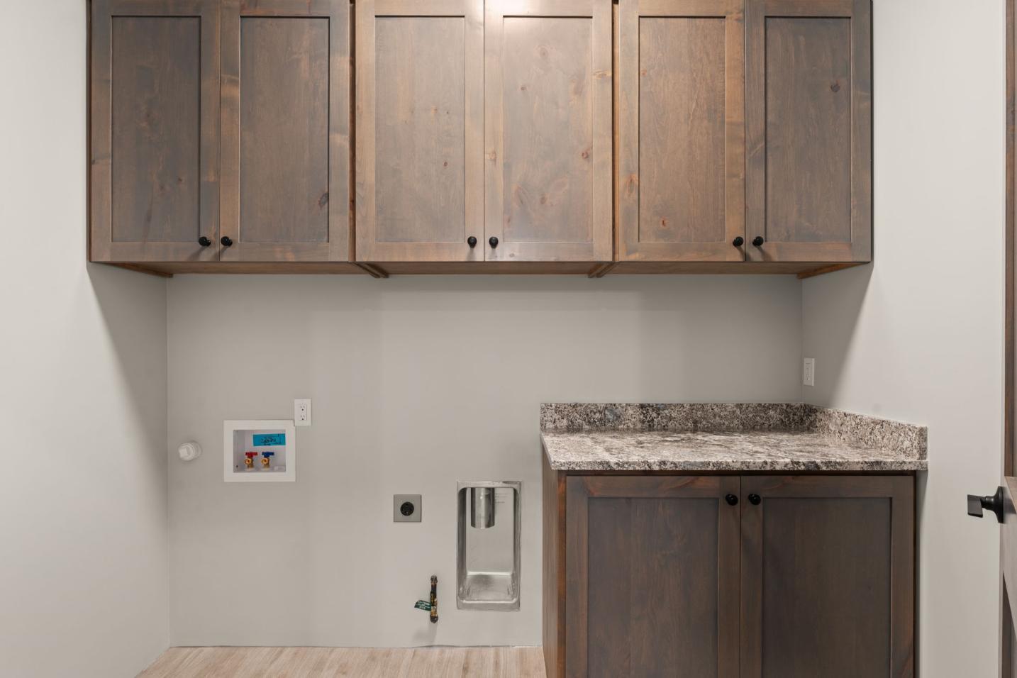 Empty laundry room with wooden cabinets and granite countertop.