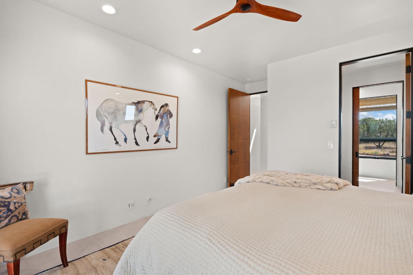 Minimalist bedroom with neutral tones and horse artwork.
