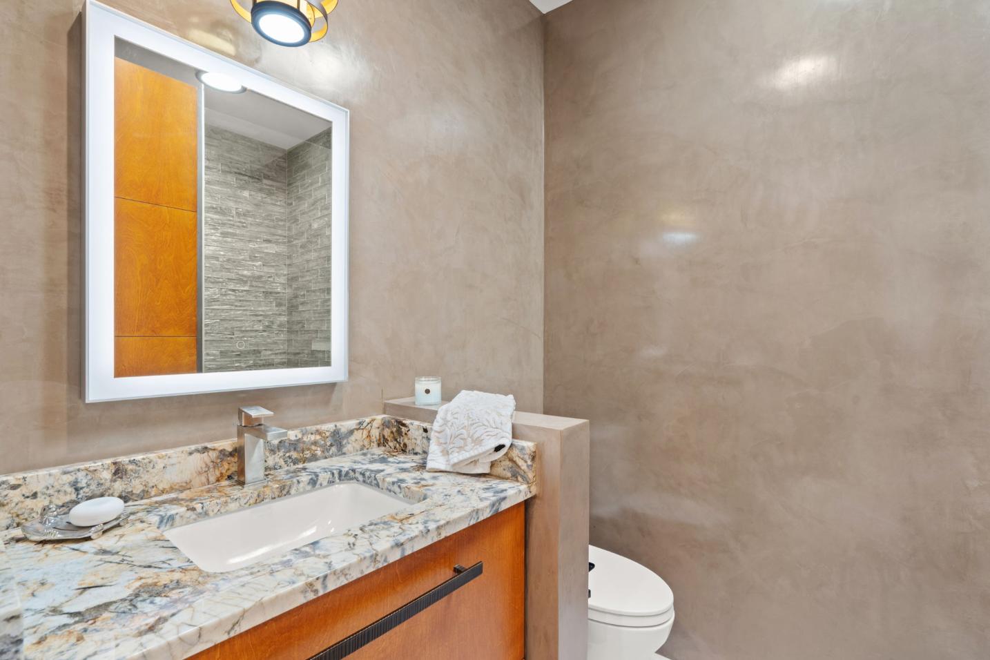 Modern bathroom with granite countertop and wooden cabinetry.