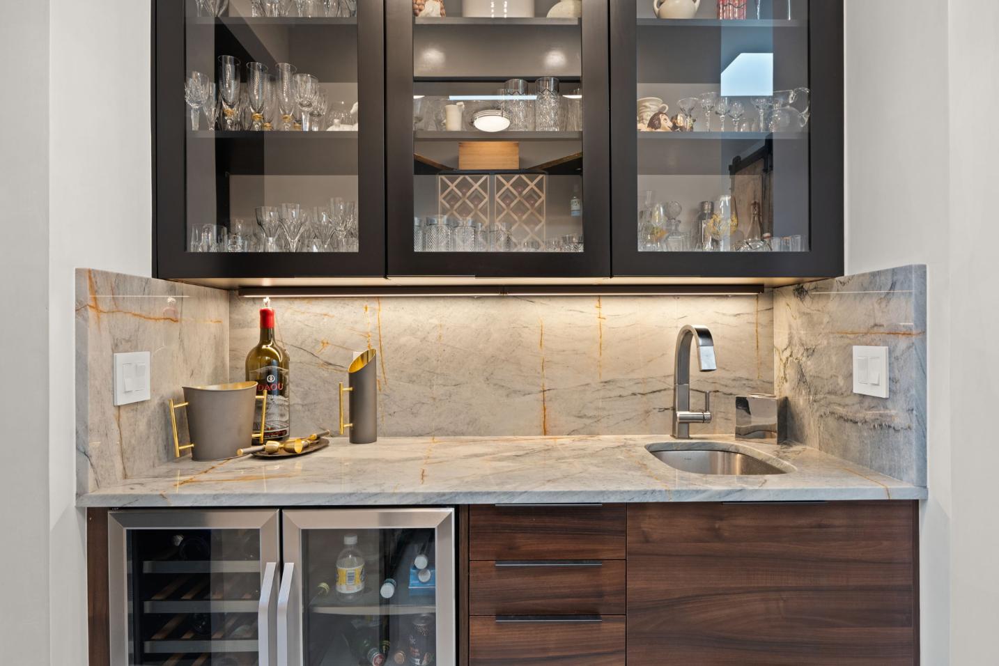 Modern kitchen bar area with glass cabinets and wine fridge.
