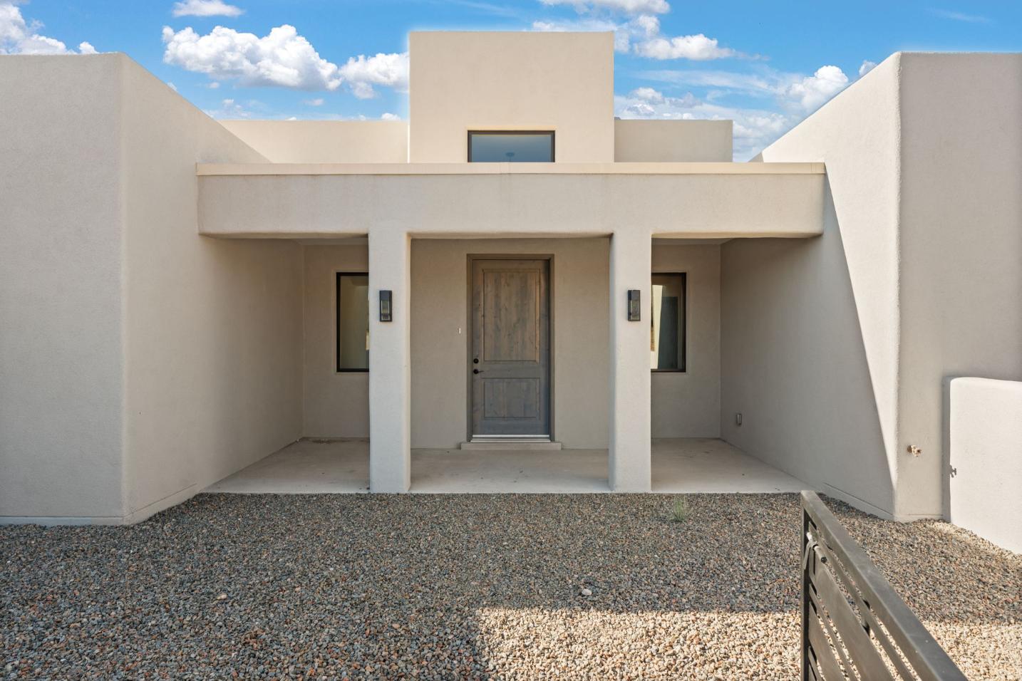 Modern beige house entrance with a central door and symmetrical windows.