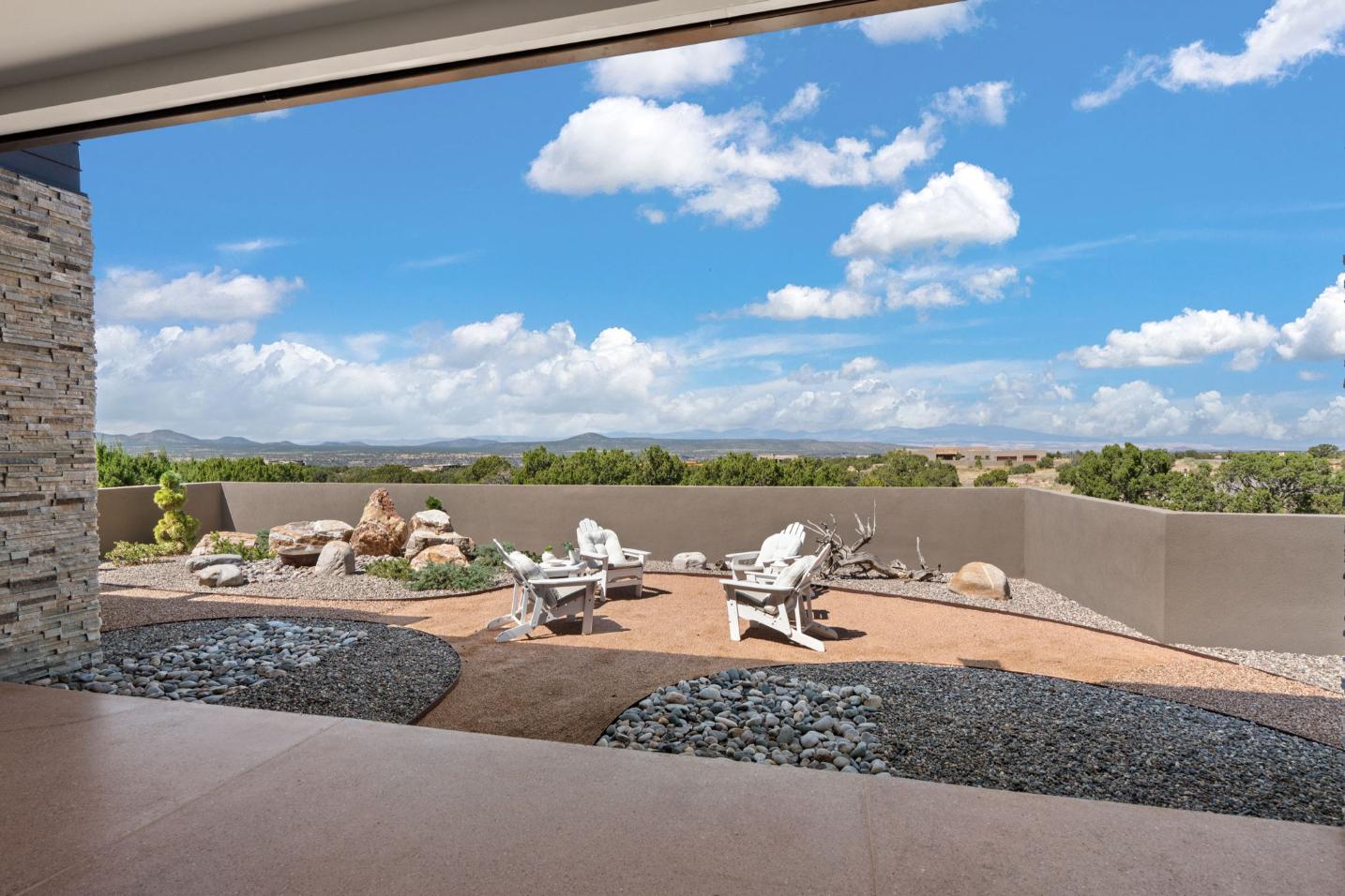 Outdoor patio with modern chairs overlooking a scenic landscape under a blue sky.