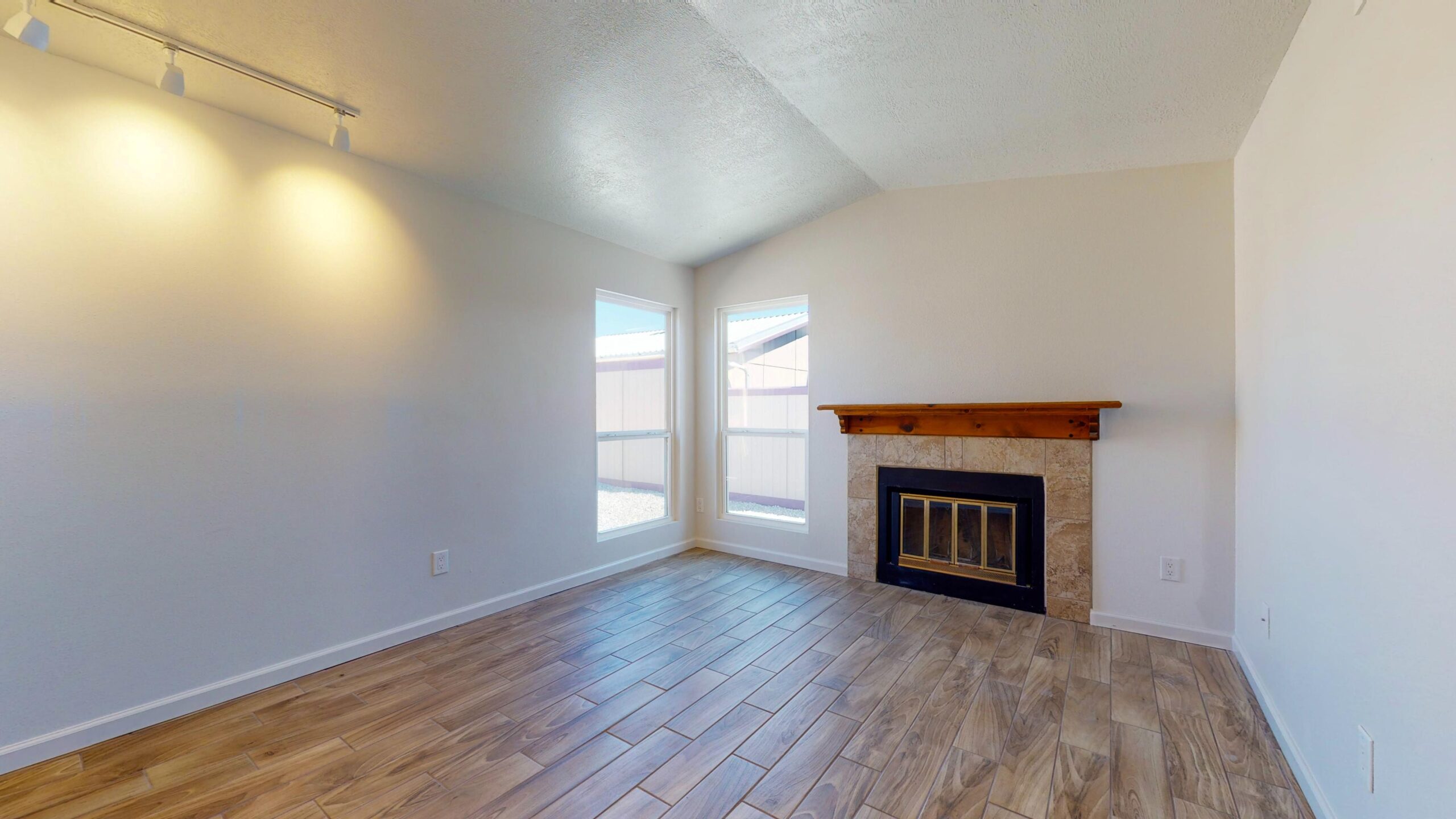 Bright, empty living room with hardwood floors and a fireplace.