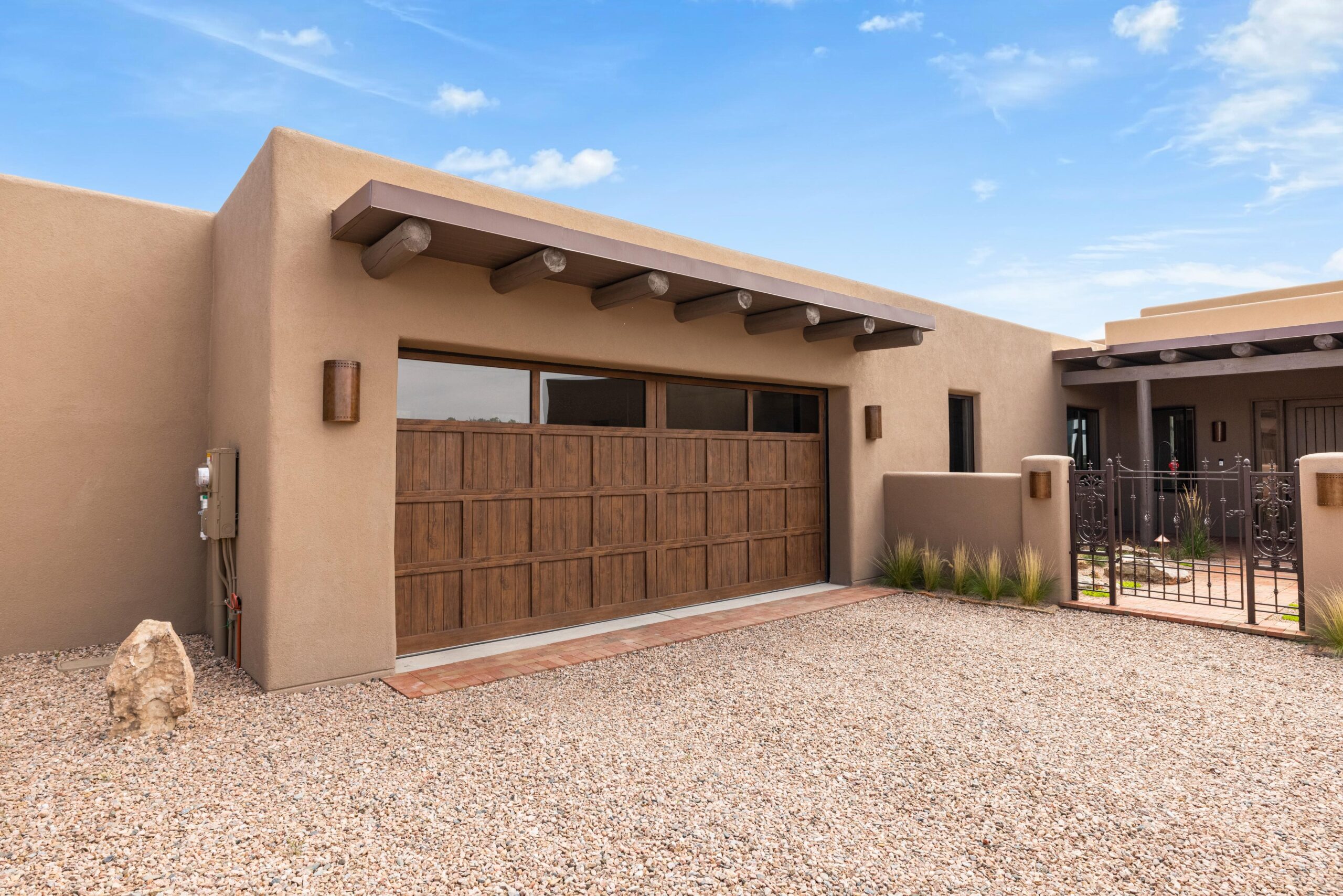 Modern southwestern style house with wooden garage doors and stucco exterior.