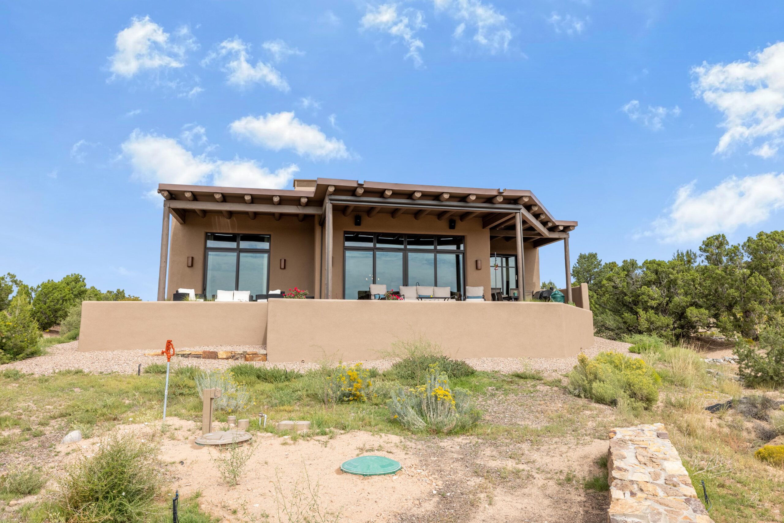 Modern house with large windows and a patio under a blue sky.