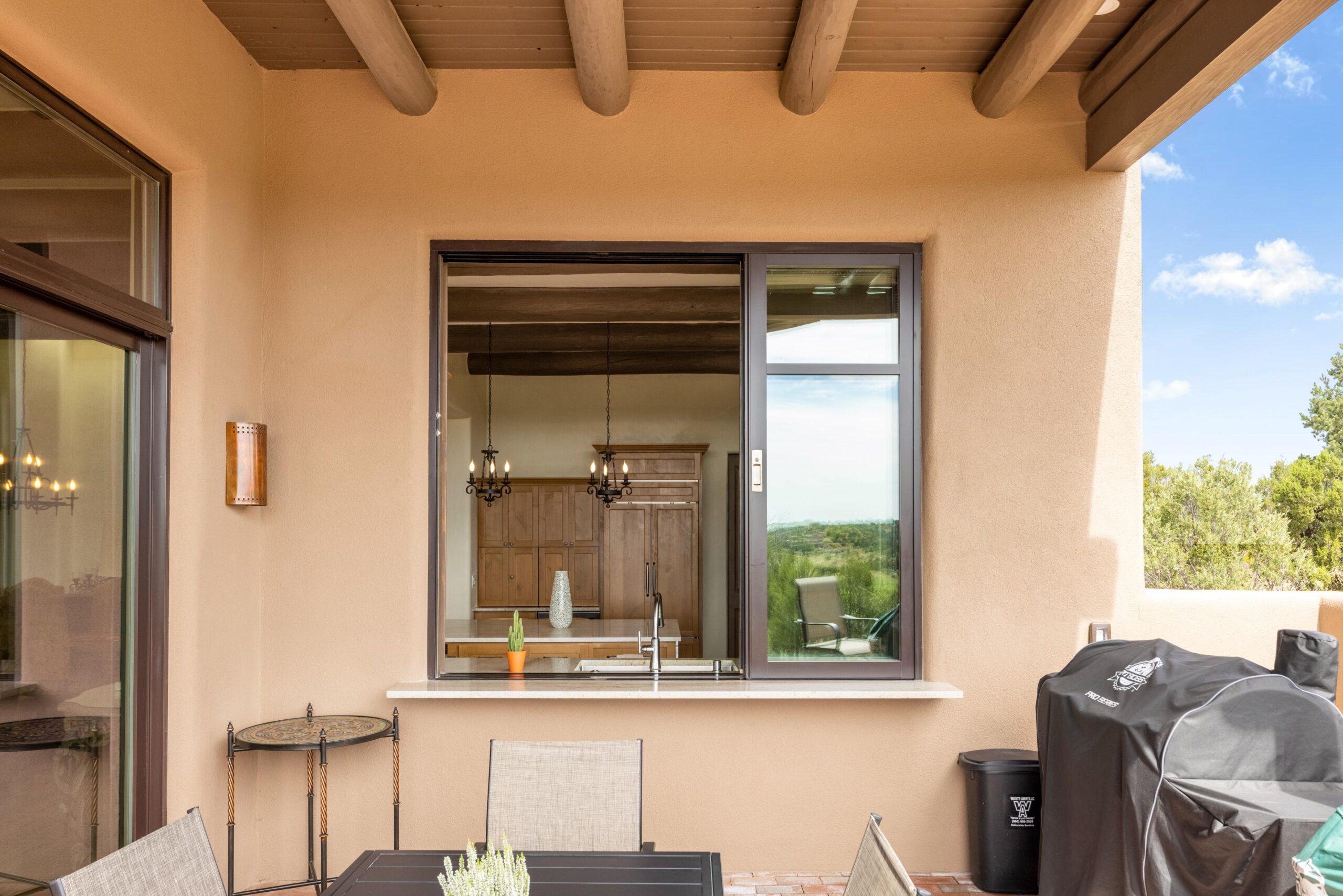 Cozy outdoor kitchen window with seating and countryside view.