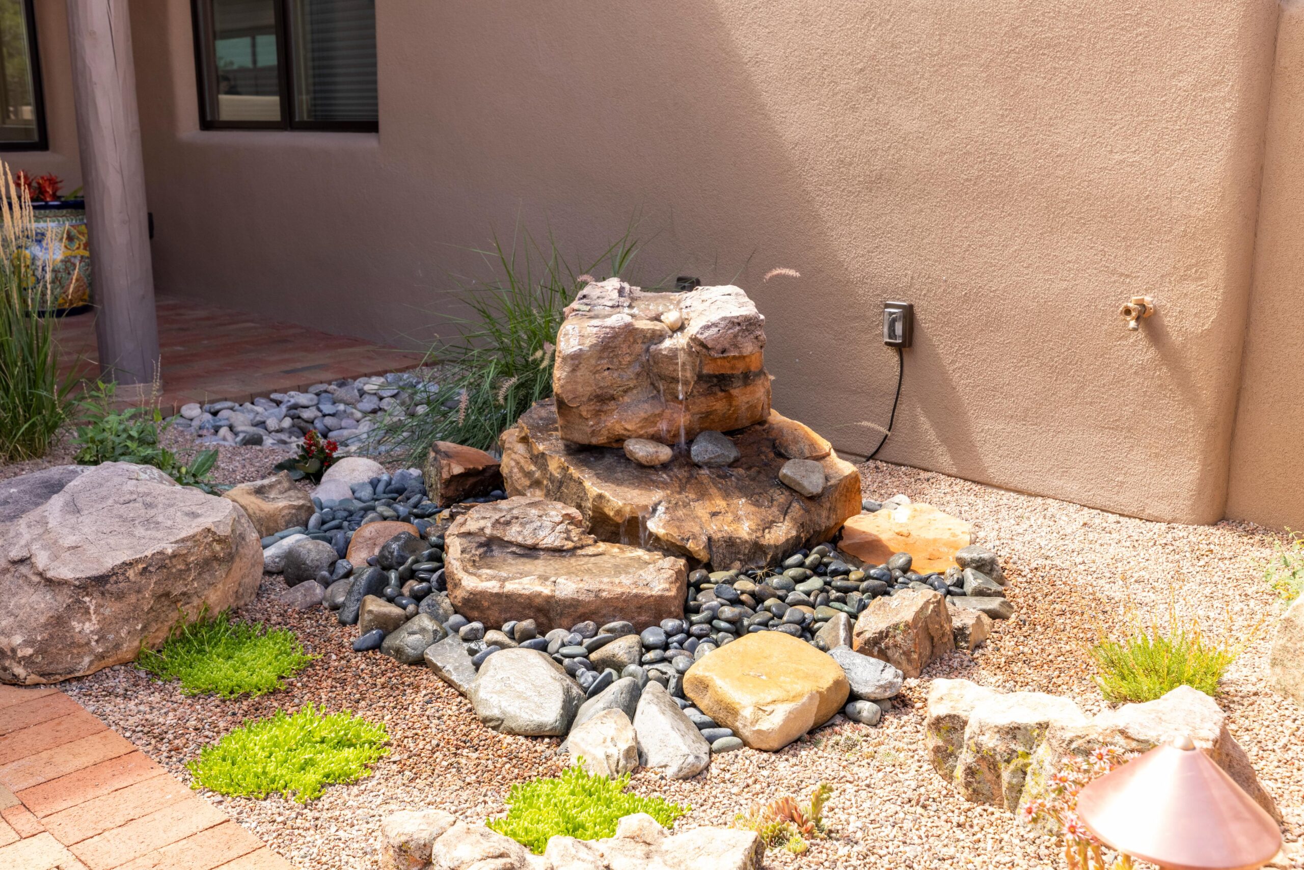 A small backyard rock waterfall feature with natural stones and plants.