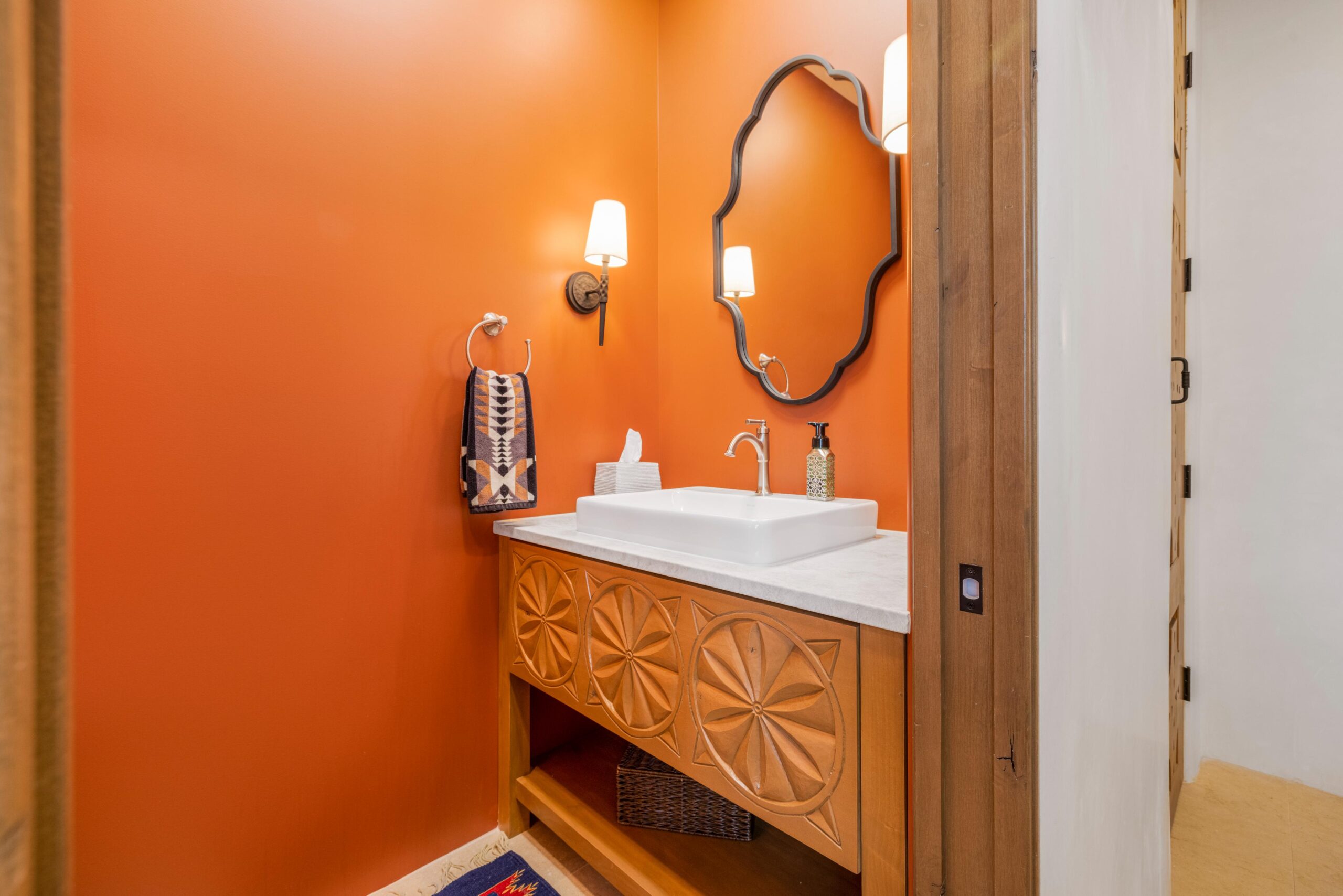 Modern bathroom with vibrant orange walls and wooden vanity.