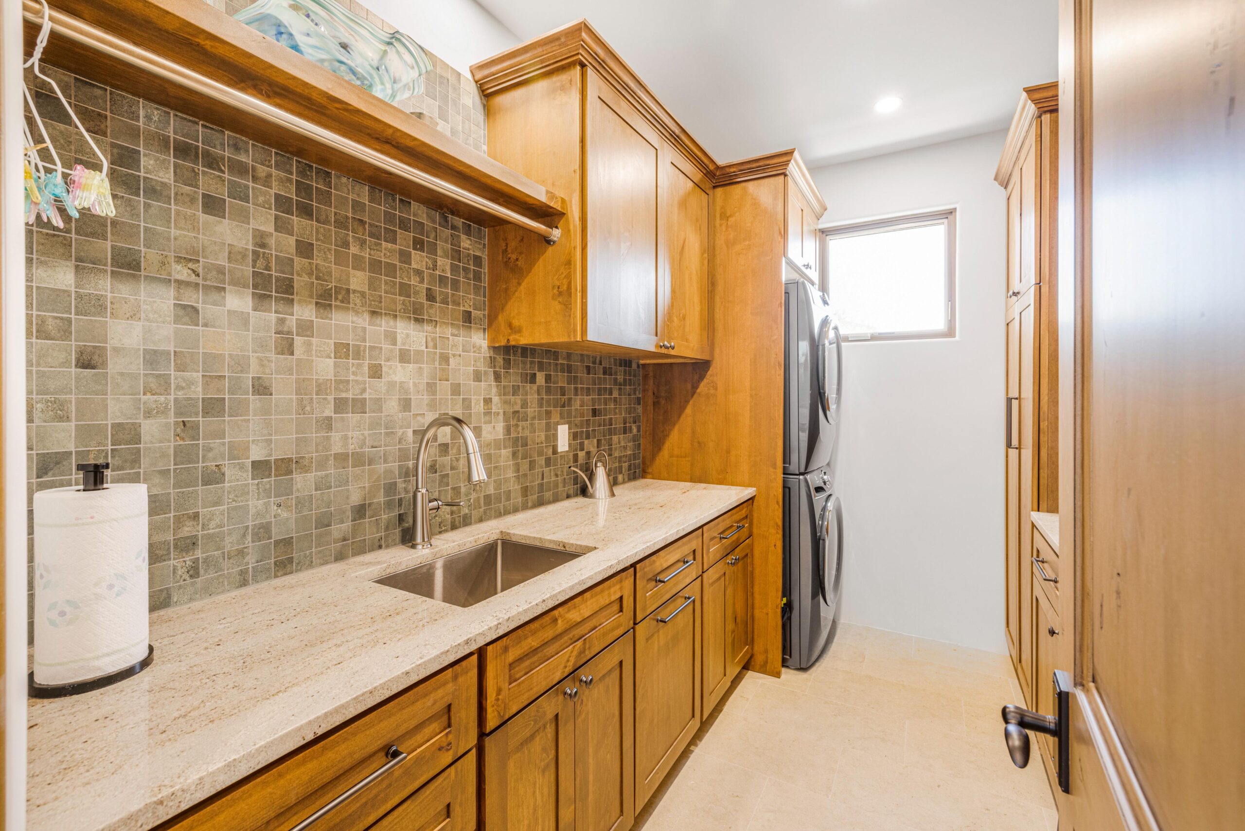 Elegant laundry room with wooden cabinets and stacked washer and dryer.
