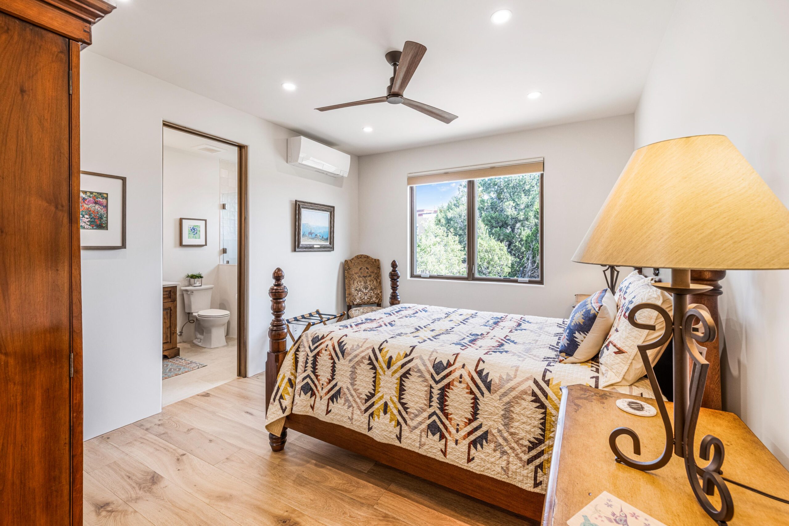 Bright bedroom with wooden floor and ceiling fan.