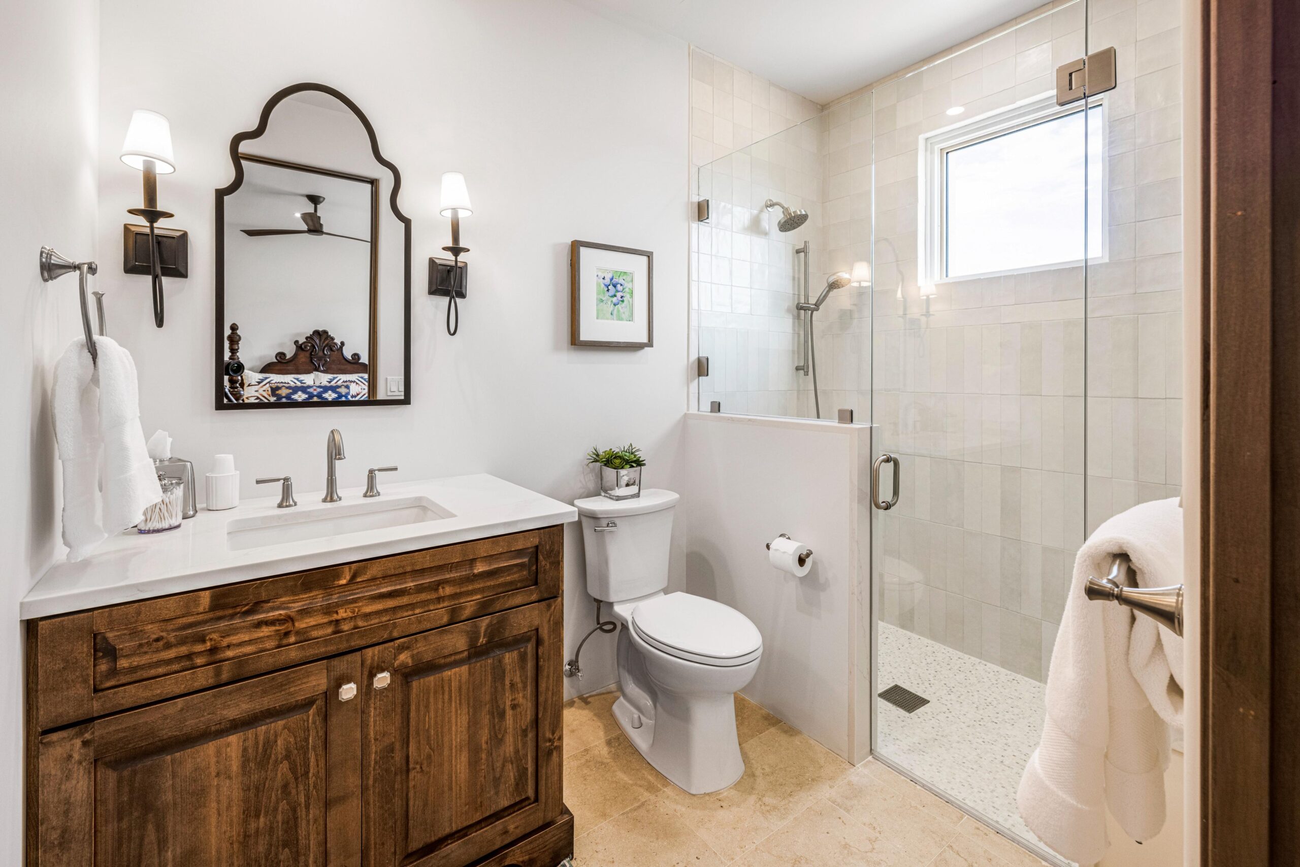 Bright bathroom with vintage wooden vanity and glass shower.