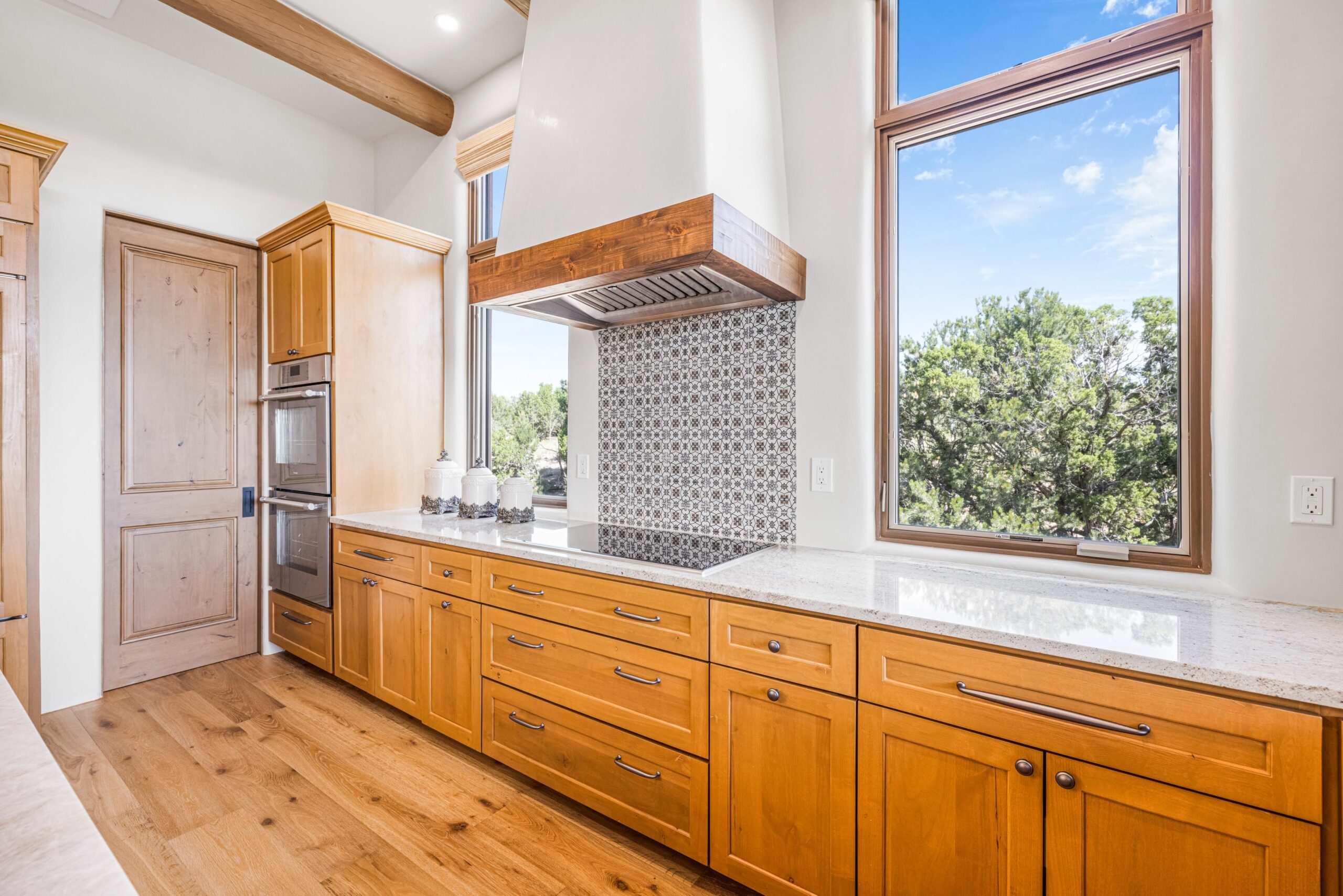 Bright kitchen with wooden cabinets and large windows overlooking greenery.