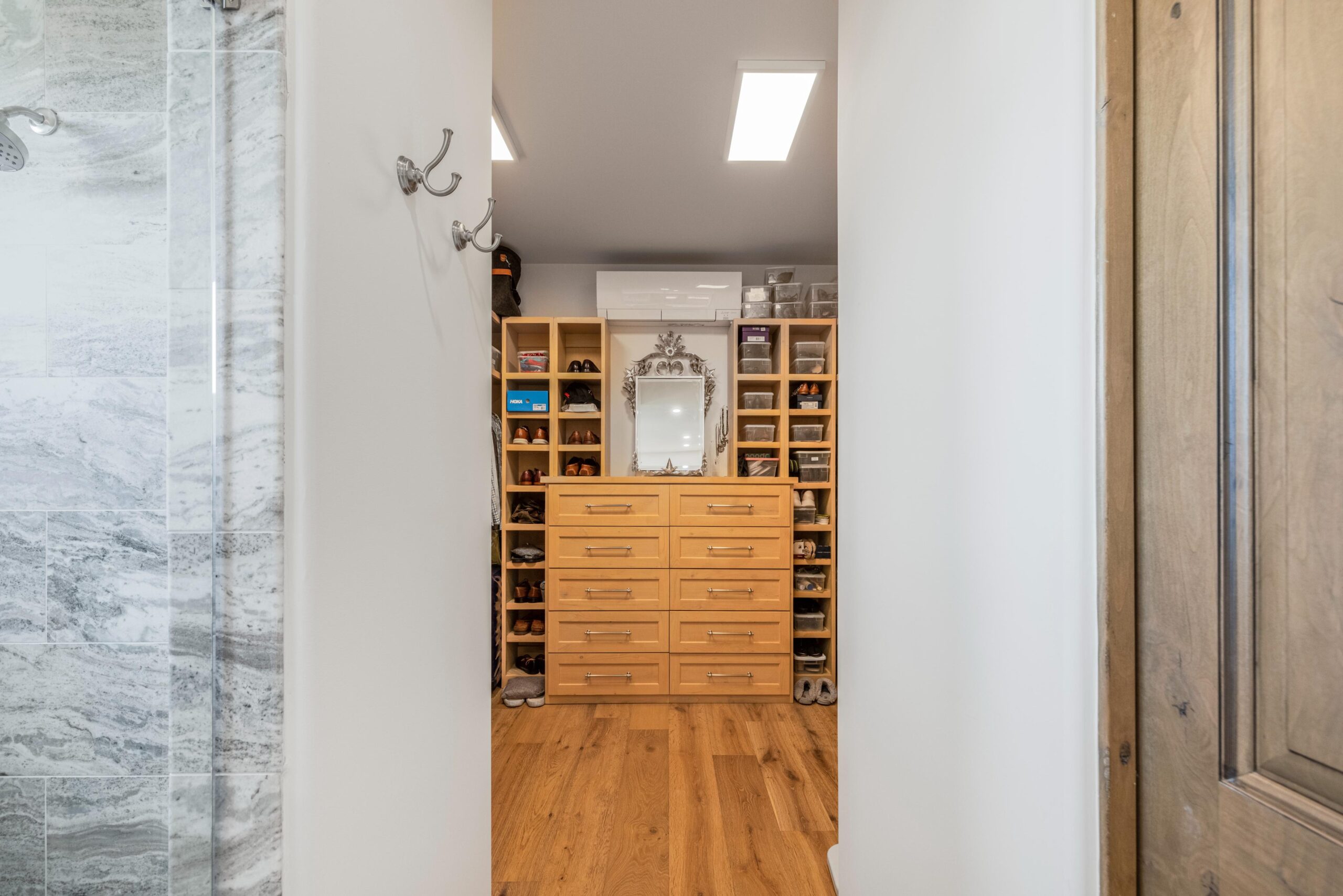 Modern walk-in closet with wooden shelves and drawers.