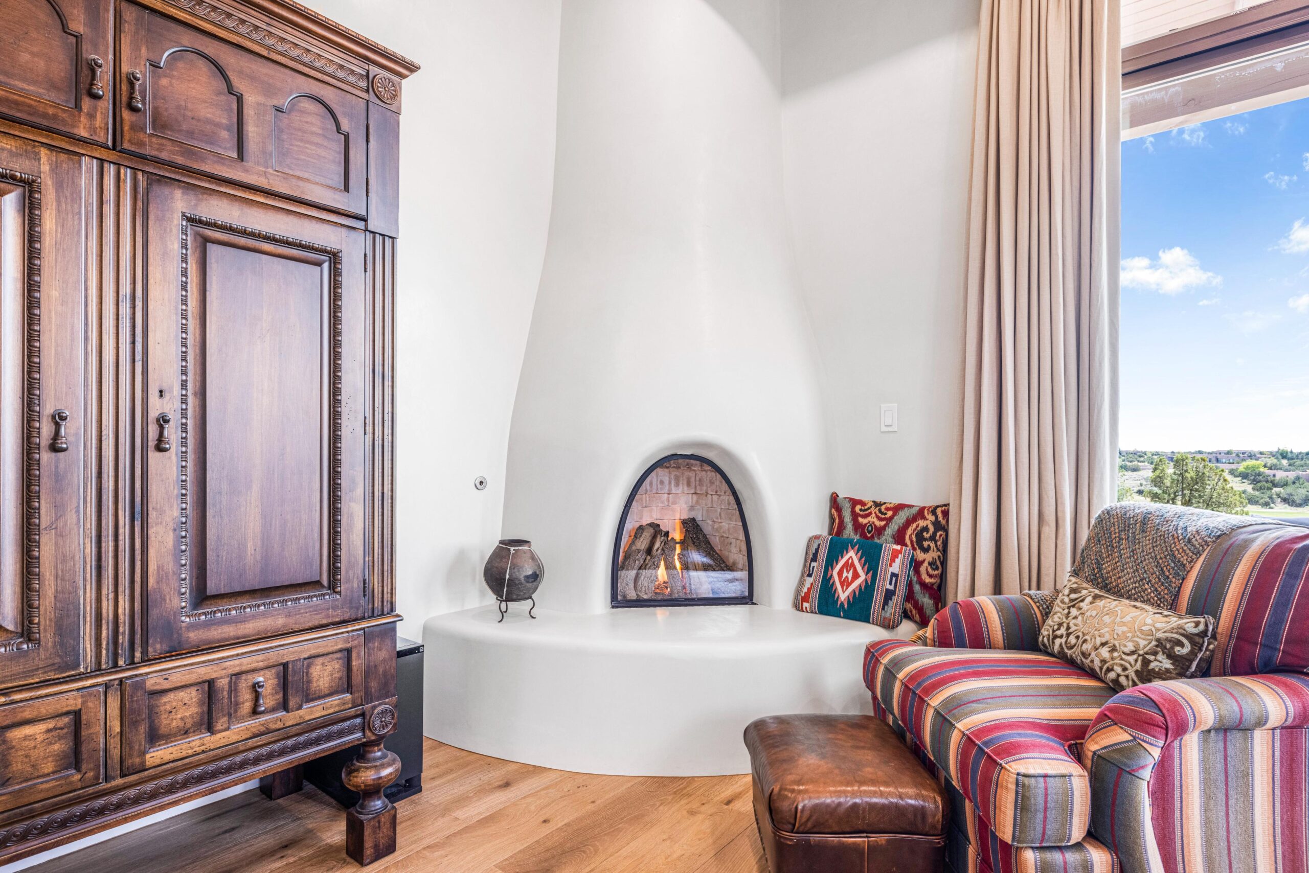 Cozy corner with a lit fireplace, cushioned seating, and rustic wooden furniture.