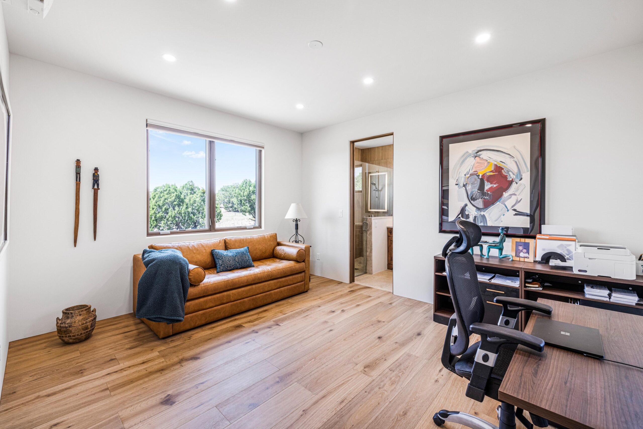 Bright home office with wooden floors and a cozy bench by the window.