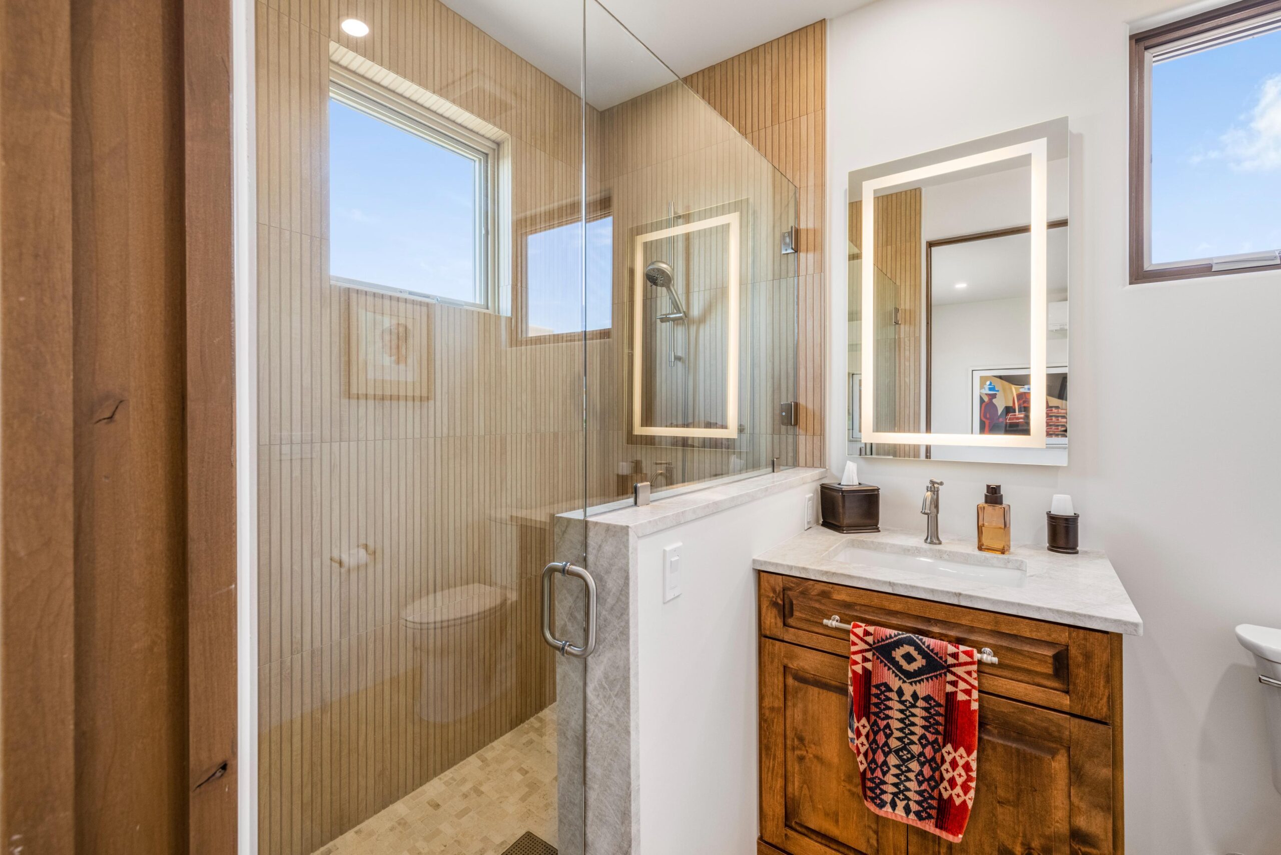 Modern bathroom with glass shower and wooden vanity.