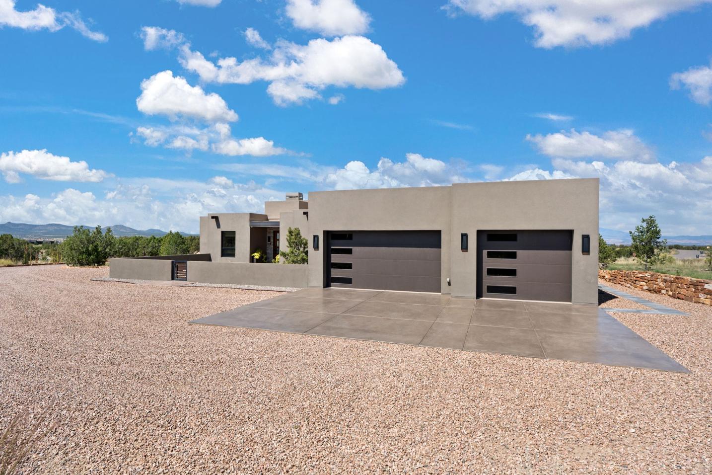 Modern desert home with a gravel driveway and blue sky.